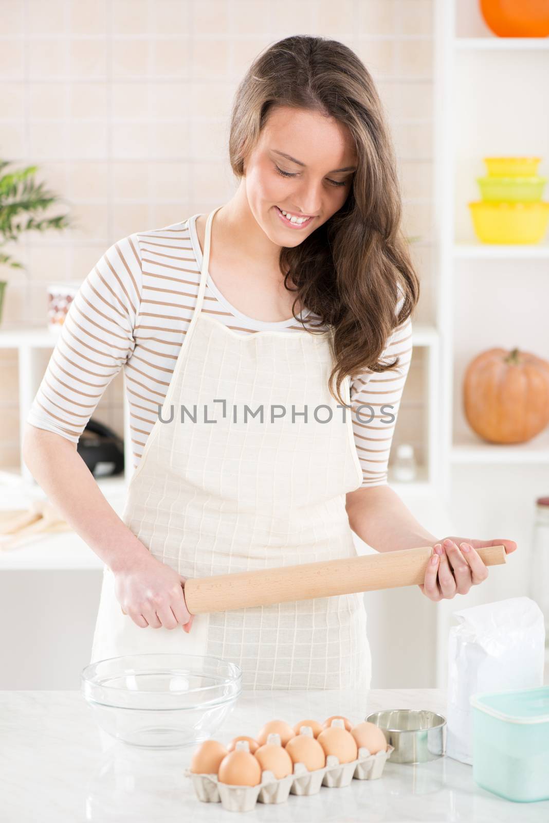 Happy young woman in the kitchen with Rolling Pin
