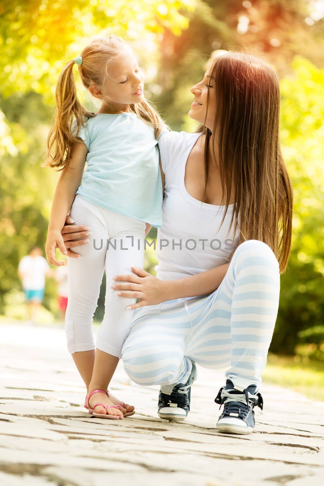 Beautiful mother and daughter having fun in the park on spring day.