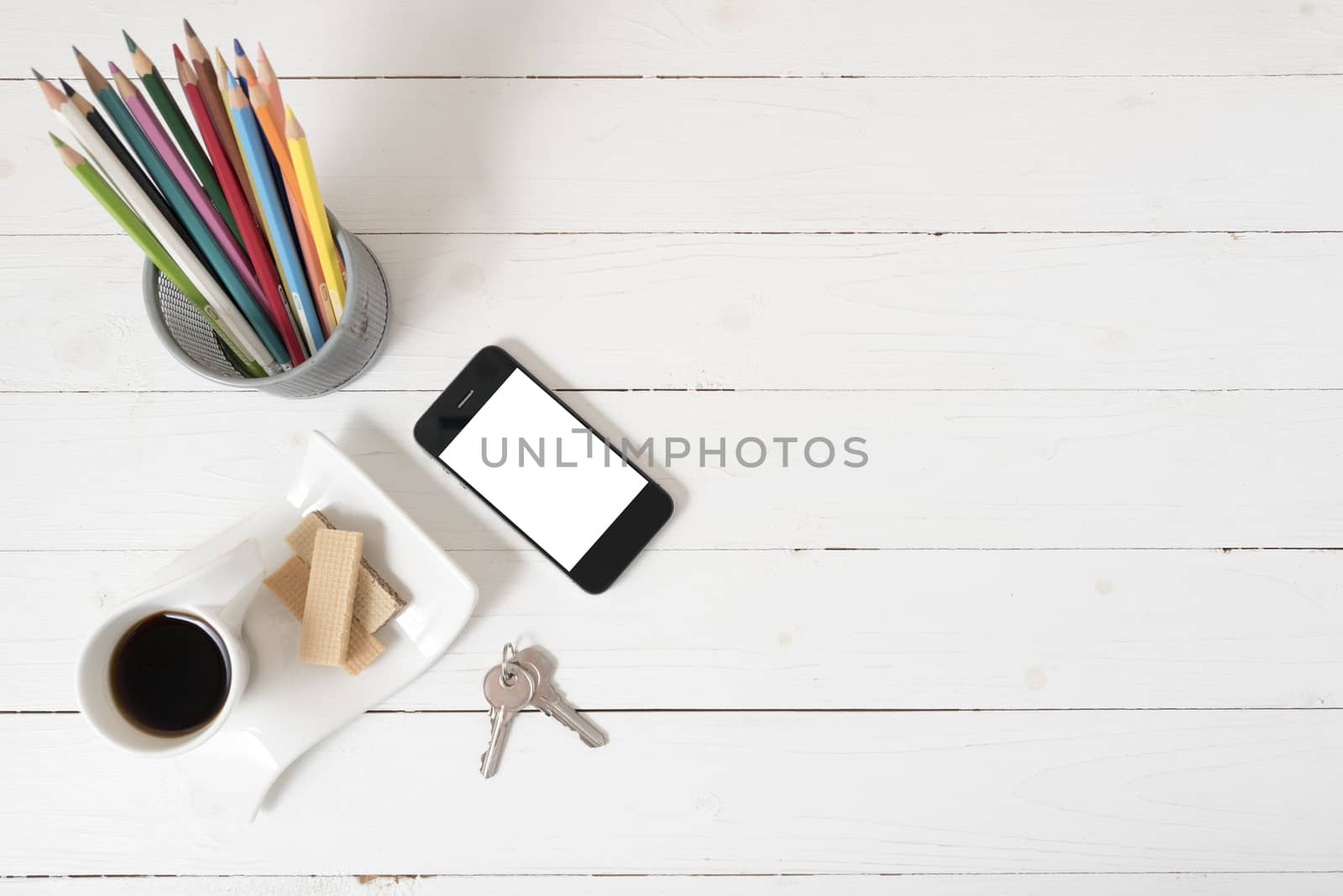 coffee cup with wafer,phone,pencil box,key on white wood background