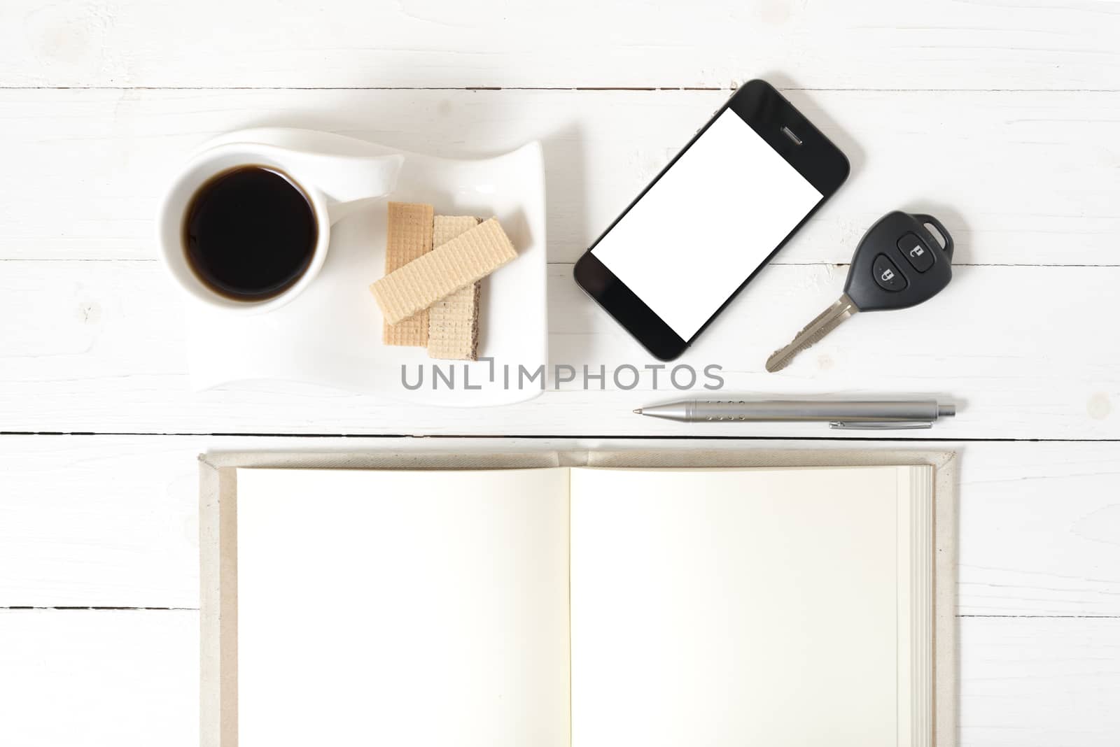 coffee cup with wafer,phone,car key,notebook on white wood background