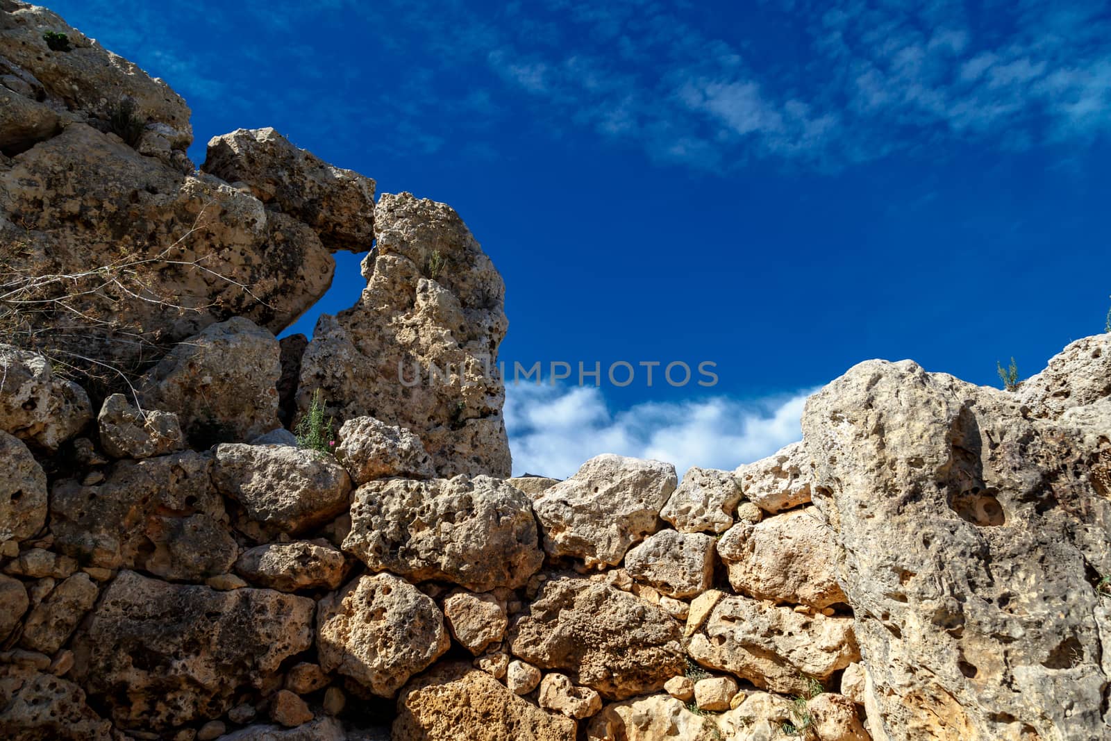 View of stone structures of ancient Ggantija Temples in Gozo Malta, on cloudy blue sky background.