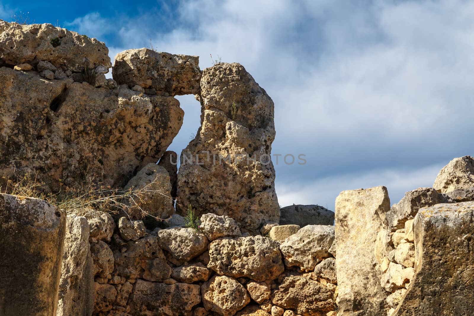 View of stone structures of ancient Ggantija Temples in Gozo Malta, on cloudy blue sky background.