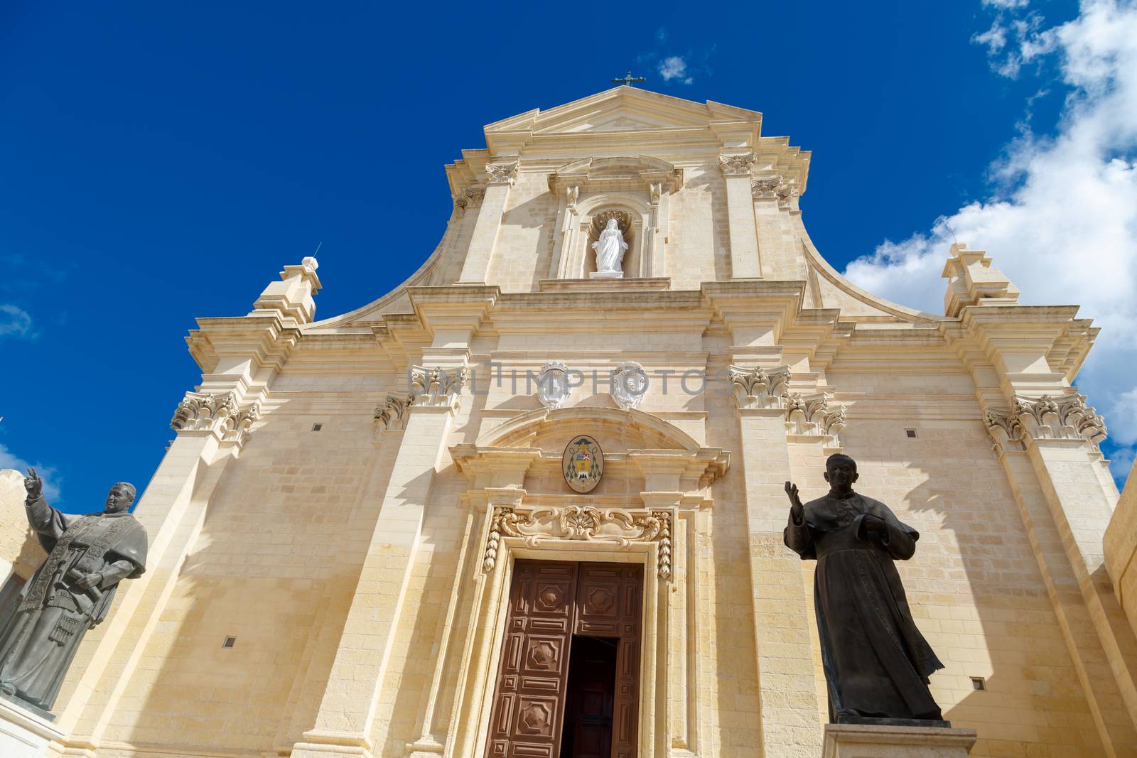 Bottom view of historical Cathedral of the Assumption in Gozo Malta, on cloudy blue sky background.