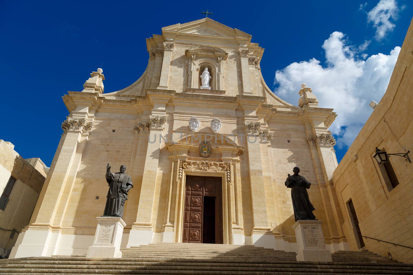 Bottom view of historical Cathedral of the Assumption in Gozo Malta, on cloudy blue sky background.