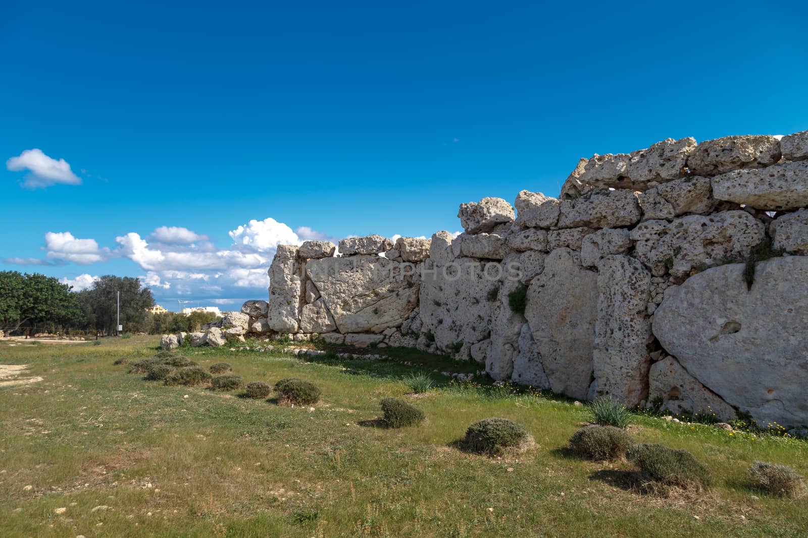 View of stone structures of ancient Ggantija Temples in Gozo Malta, on cloudy blue sky background.