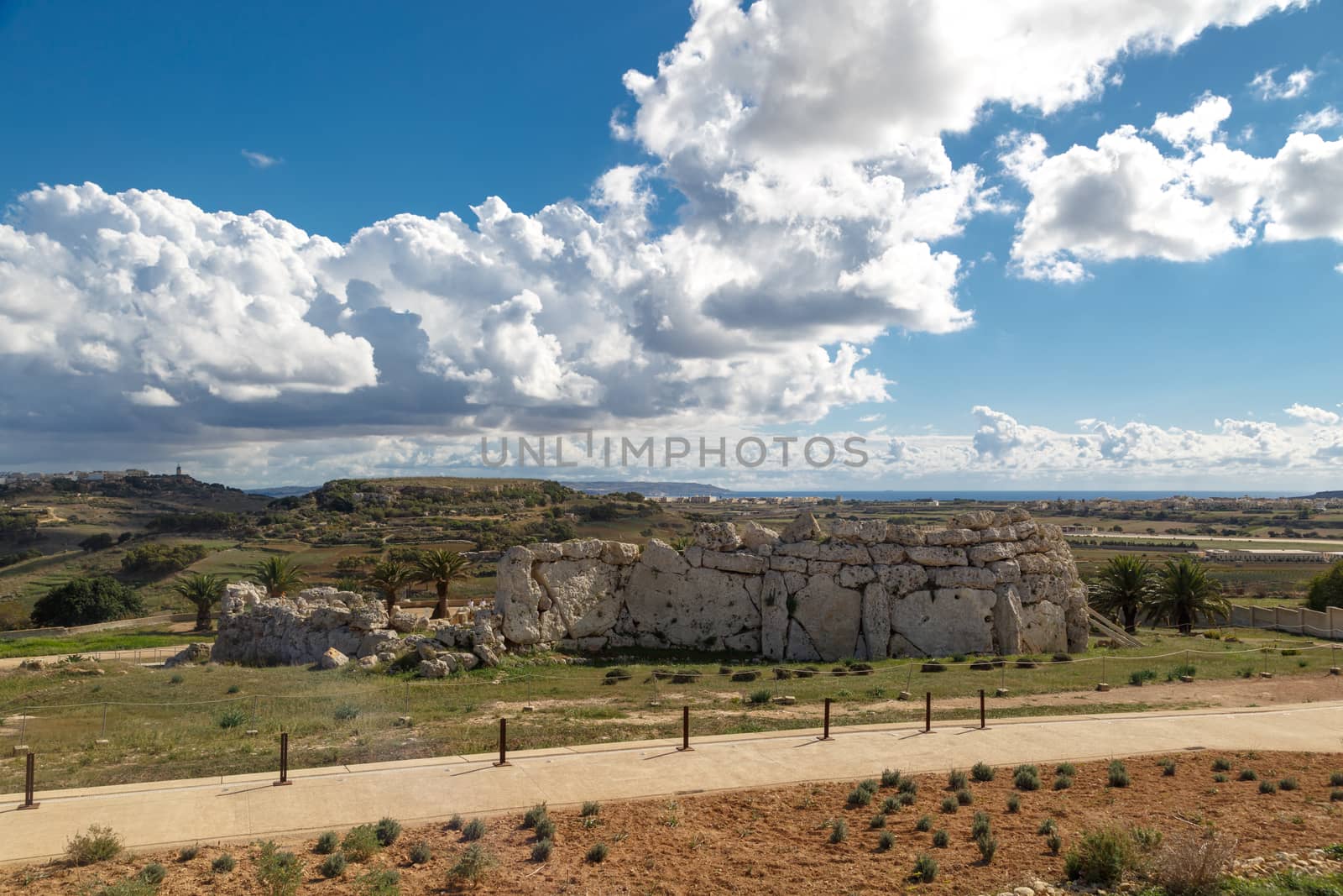 View of stone structures of ancient Ggantija Temples in Gozo Malta, on cloudy blue sky background.