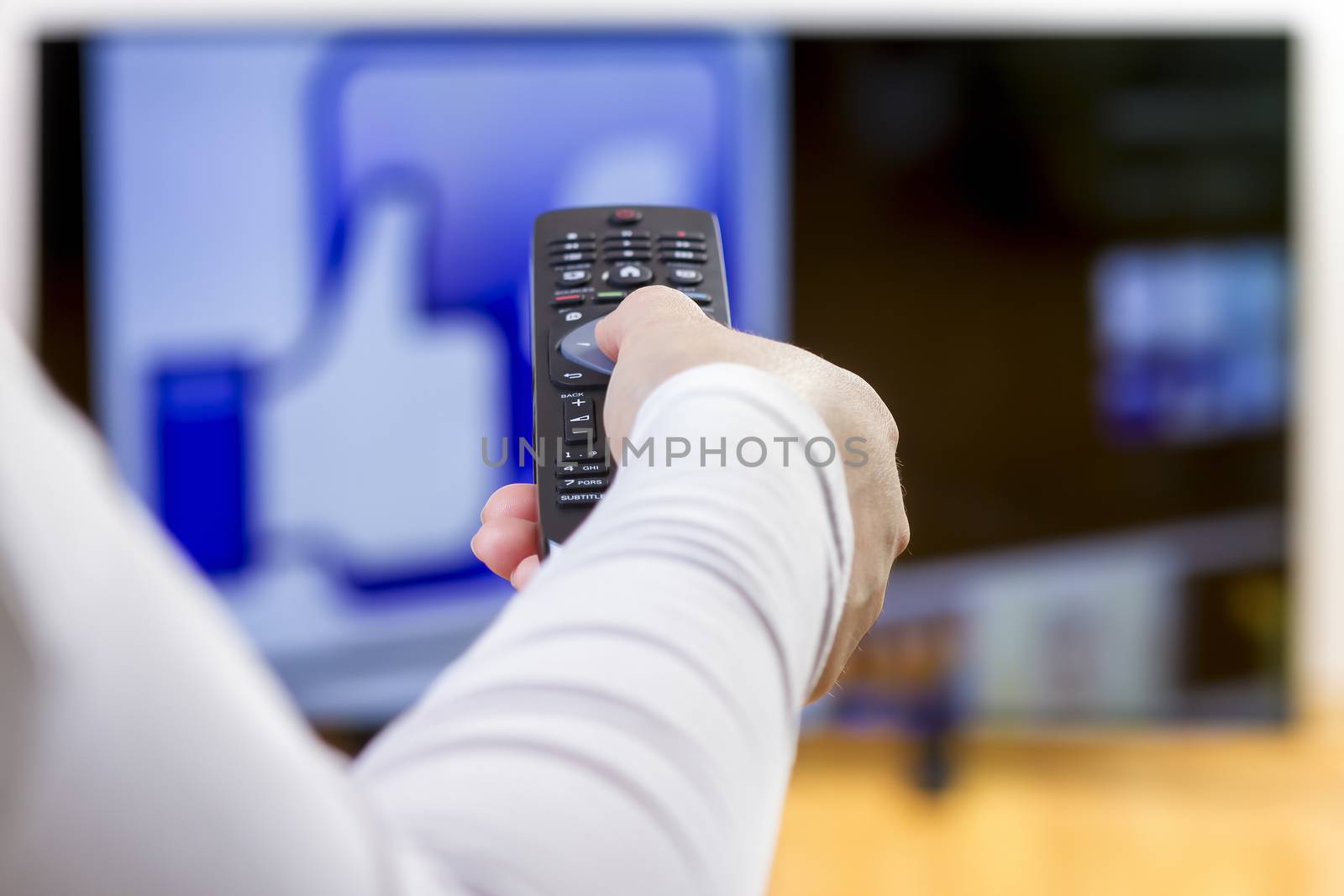 Closeup on woman hand holding remote control  and surfing internet on television. Focus on the remote control.