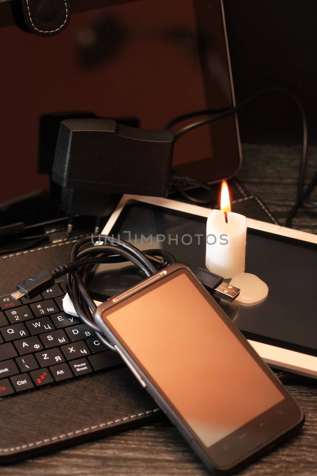 Blackout concept. Lighting candle on set of modern electronic gadgets
