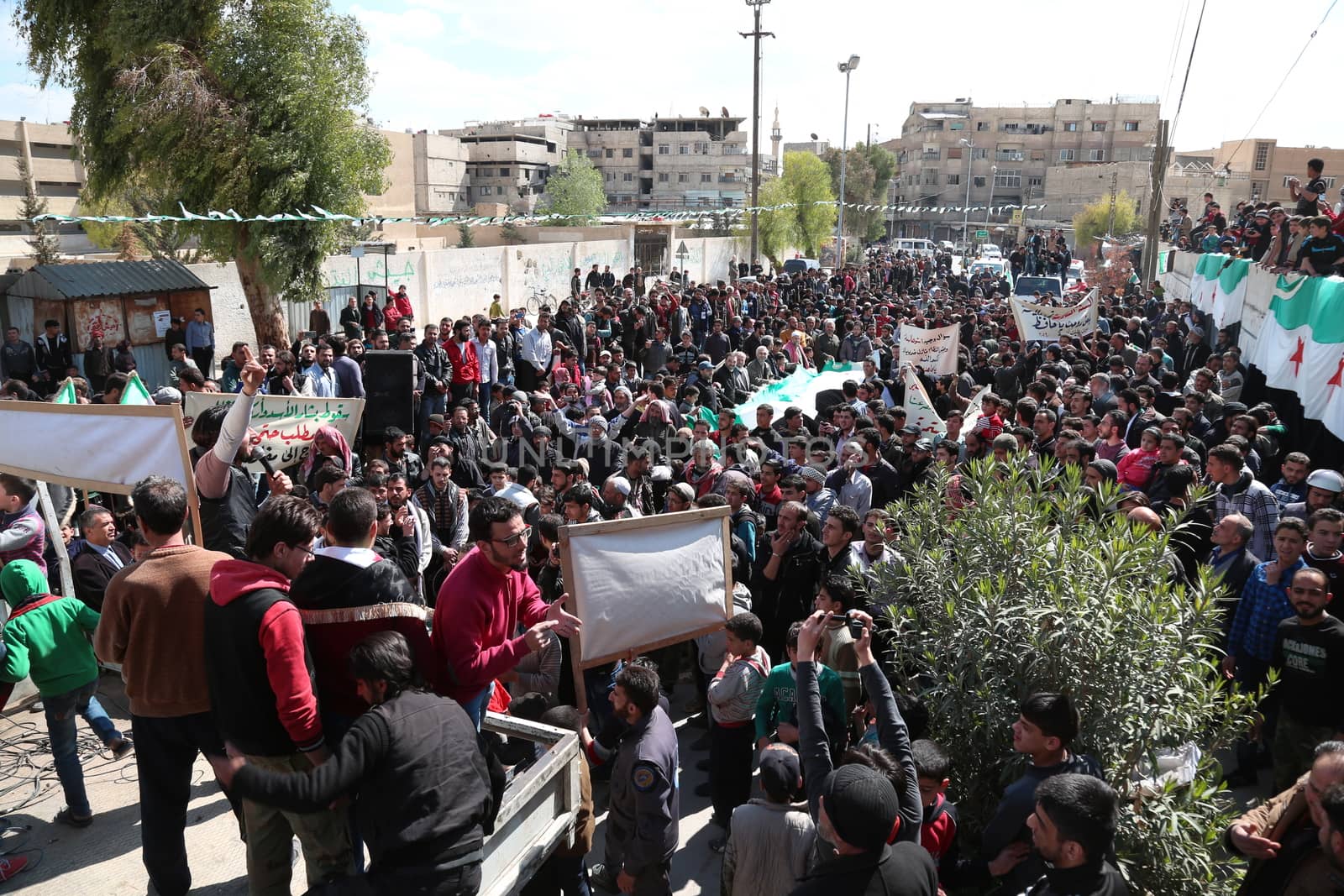 SYRIA, Saqba: Protesters hold pre-Baath Syrian flags, adopted during the uprising in 2011, and placards during an anti-regime demonstration in the rebel-held town of Saqba, on the outskirts of the Syrian capital Damascus, on March 18, 2016. Syria's war is entering its sixth year with a glimmer of hope that a landmark ceasefire and a push for peace could help resolve a conflict that has sent hundreds of thousands fleeing to Europe. The conflict began with anti-regime protests in mid-March 2011 and spiralled into a bloody war after a harsh government crackdown on demonstrators.
