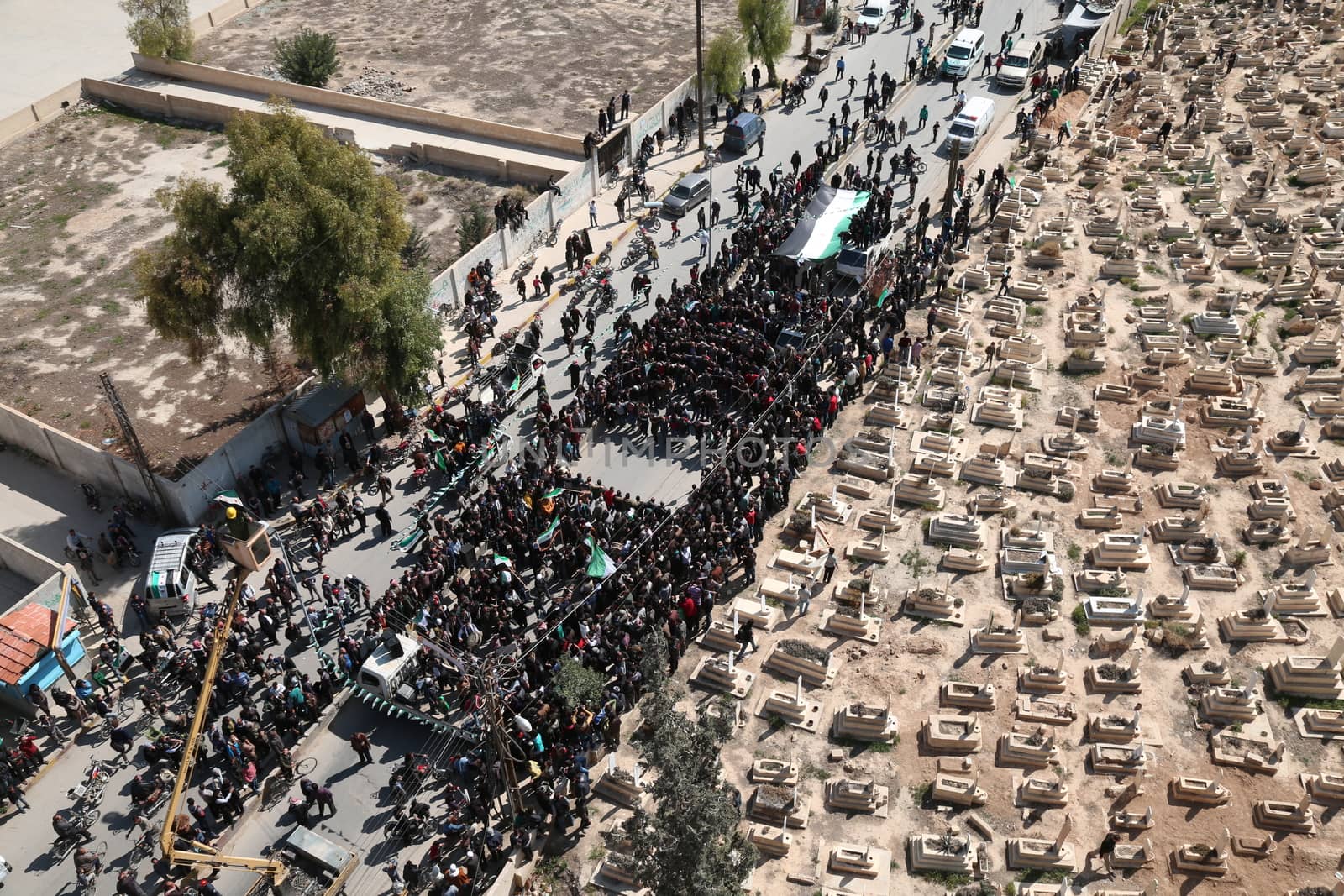SYRIA, Saqba: Protesters hold pre-Baath Syrian flags, adopted during the uprising in 2011, and placards during an anti-regime demonstration along cemetery of the rebel-held town of Saqba, on the outskirts of the Syrian capital Damascus, on March 18, 2016. Syria's war is entering its sixth year with a glimmer of hope that a landmark ceasefire and a push for peace could help resolve a conflict that has sent hundreds of thousands fleeing to Europe. The conflict began with anti-regime protests in mid-March 2011 and spiralled into a bloody war after a harsh government crackdown on demonstrators.