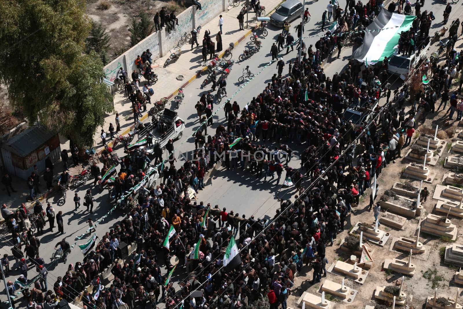 SYRIA, Saqba: Protesters hold pre-Baath Syrian flags, adopted during the uprising in 2011, and placards during an anti-regime demonstration along cemetery of the rebel-held town of Saqba, on the outskirts of the Syrian capital Damascus, on March 18, 2016. Syria's war is entering its sixth year with a glimmer of hope that a landmark ceasefire and a push for peace could help resolve a conflict that has sent hundreds of thousands fleeing to Europe. The conflict began with anti-regime protests in mid-March 2011 and spiralled into a bloody war after a harsh government crackdown on demonstrators.