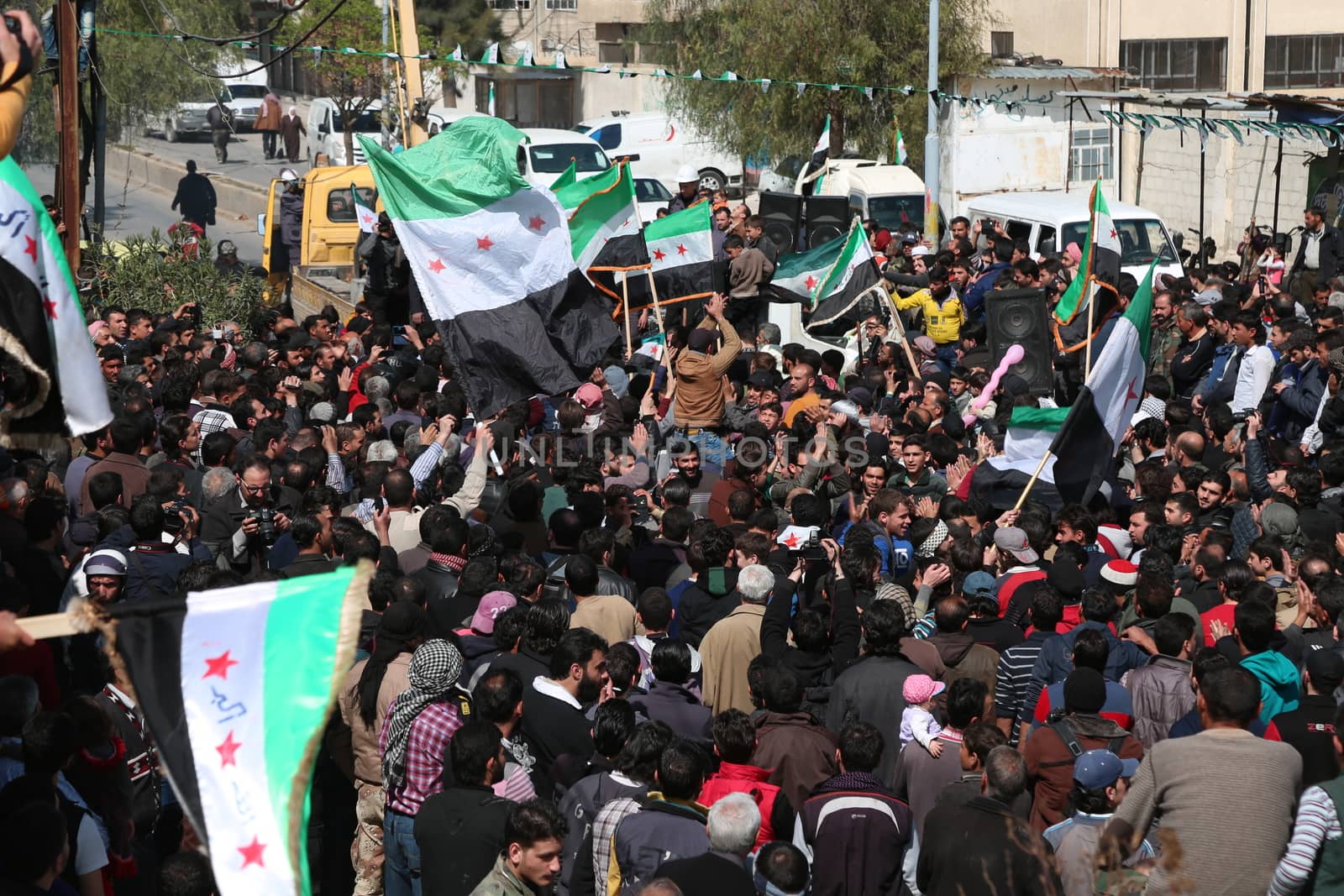 SYRIA, Saqba: Protesters hold pre-Baath Syrian flags, adopted during the uprising in 2011, and placards during an anti-regime demonstration in the rebel-held town of Saqba, on the outskirts of the Syrian capital Damascus, on March 18, 2016. Syria's war is entering its sixth year with a glimmer of hope that a landmark ceasefire and a push for peace could help resolve a conflict that has sent hundreds of thousands fleeing to Europe. The conflict began with anti-regime protests in mid-March 2011 and spiralled into a bloody war after a harsh government crackdown on demonstrators.