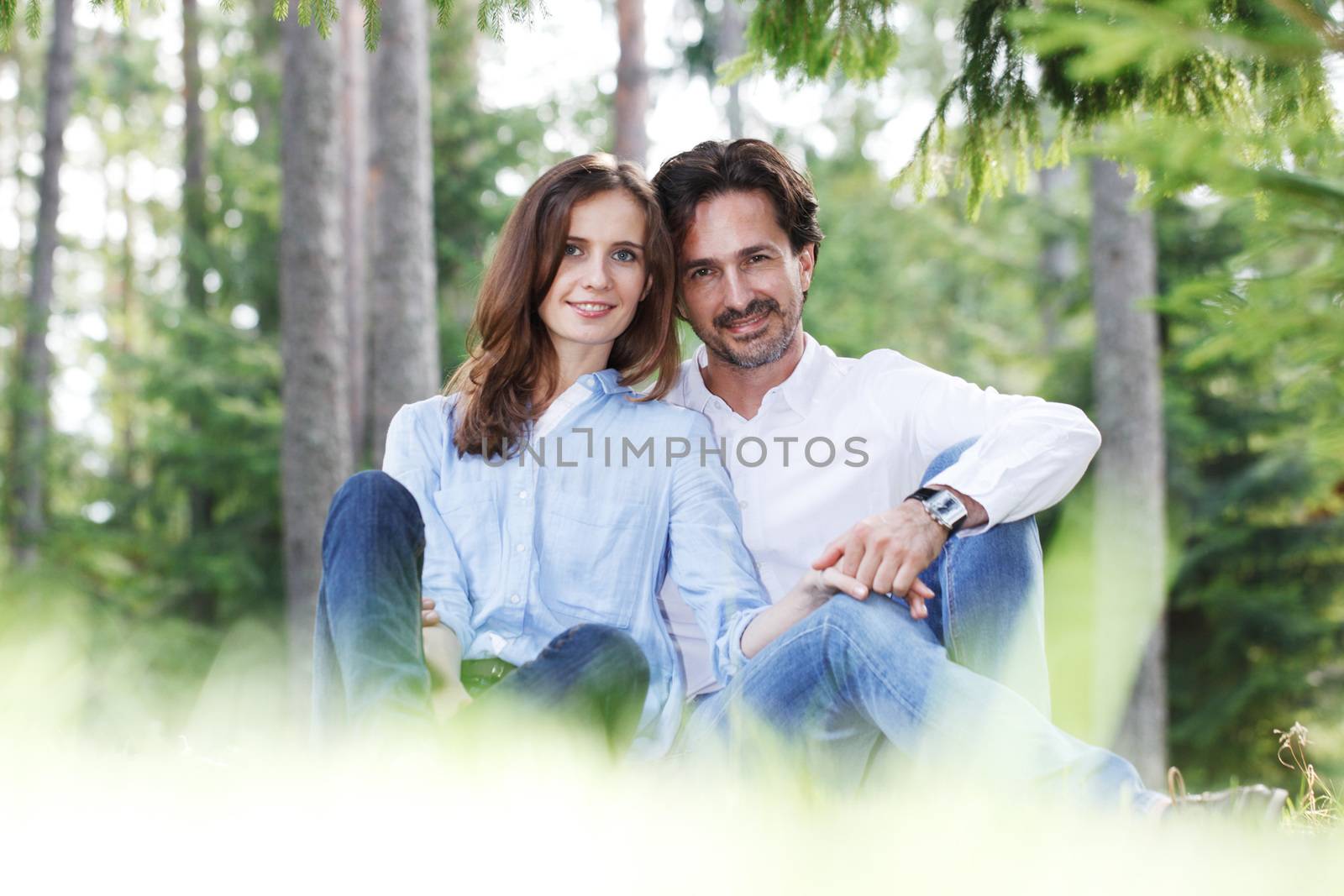 Happy couple sitting on grass in summer park