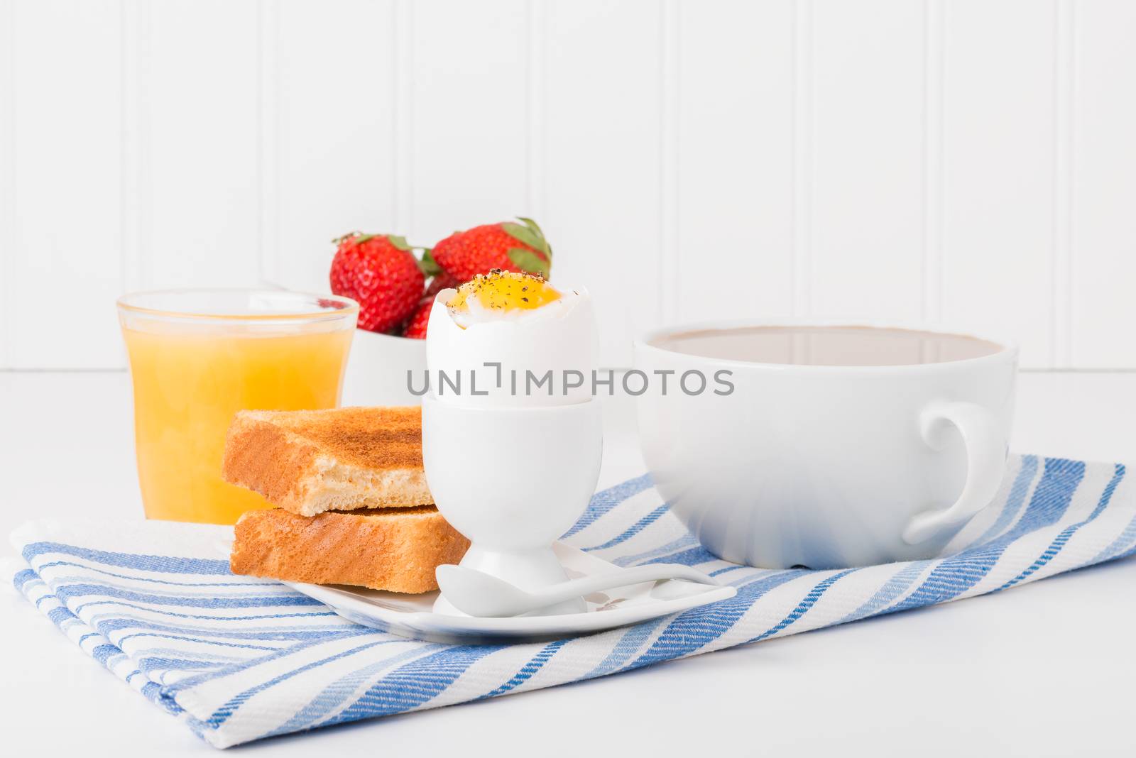 Soft boiled egg with toast served with coffee and juice.