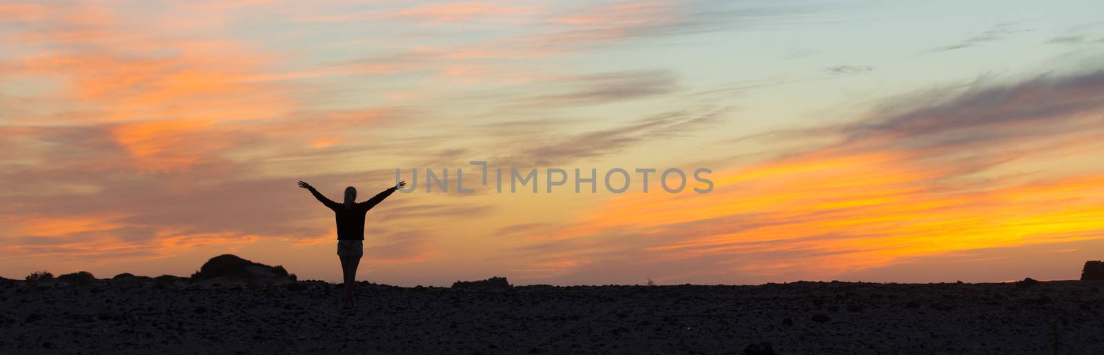 Woman enjoying freedom at sunset. by kasto