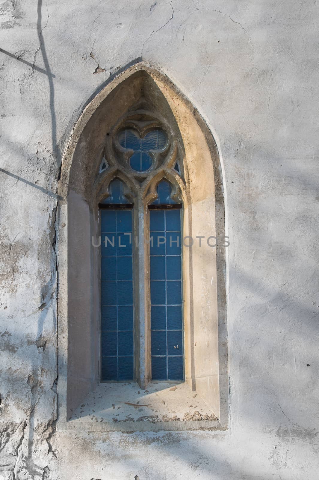 Original gothic window with a stone frame and a glass reflecting the sky. Church of Saint Cross in Devin, Bratislava, Slovakia.