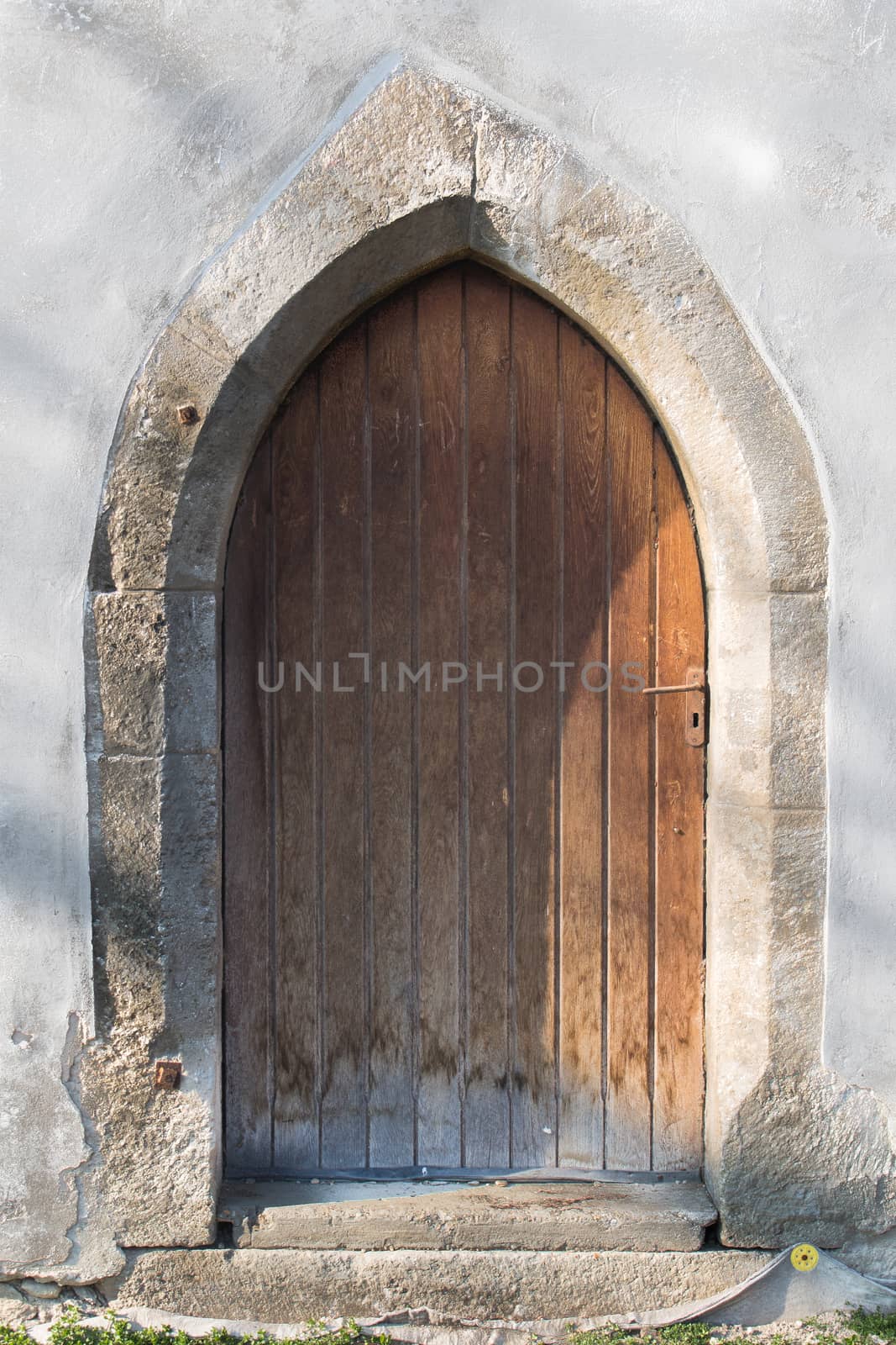 Gothic gate with a stone frame and wooden heavy door. Church of Saint Cross in Devin, Bratislava, Slovakia.