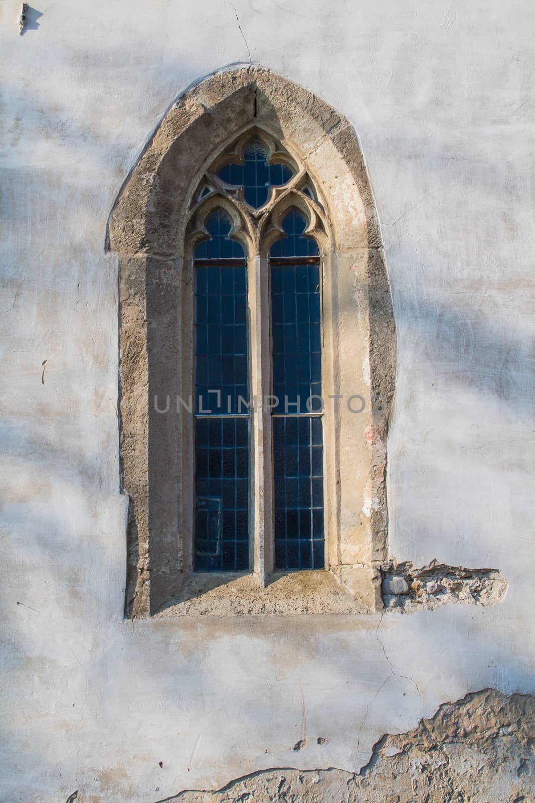 Original gothic window with a stone frame and a glass reflecting the sky. Church of Saint Cross in Devin, Bratislava, Slovakia.