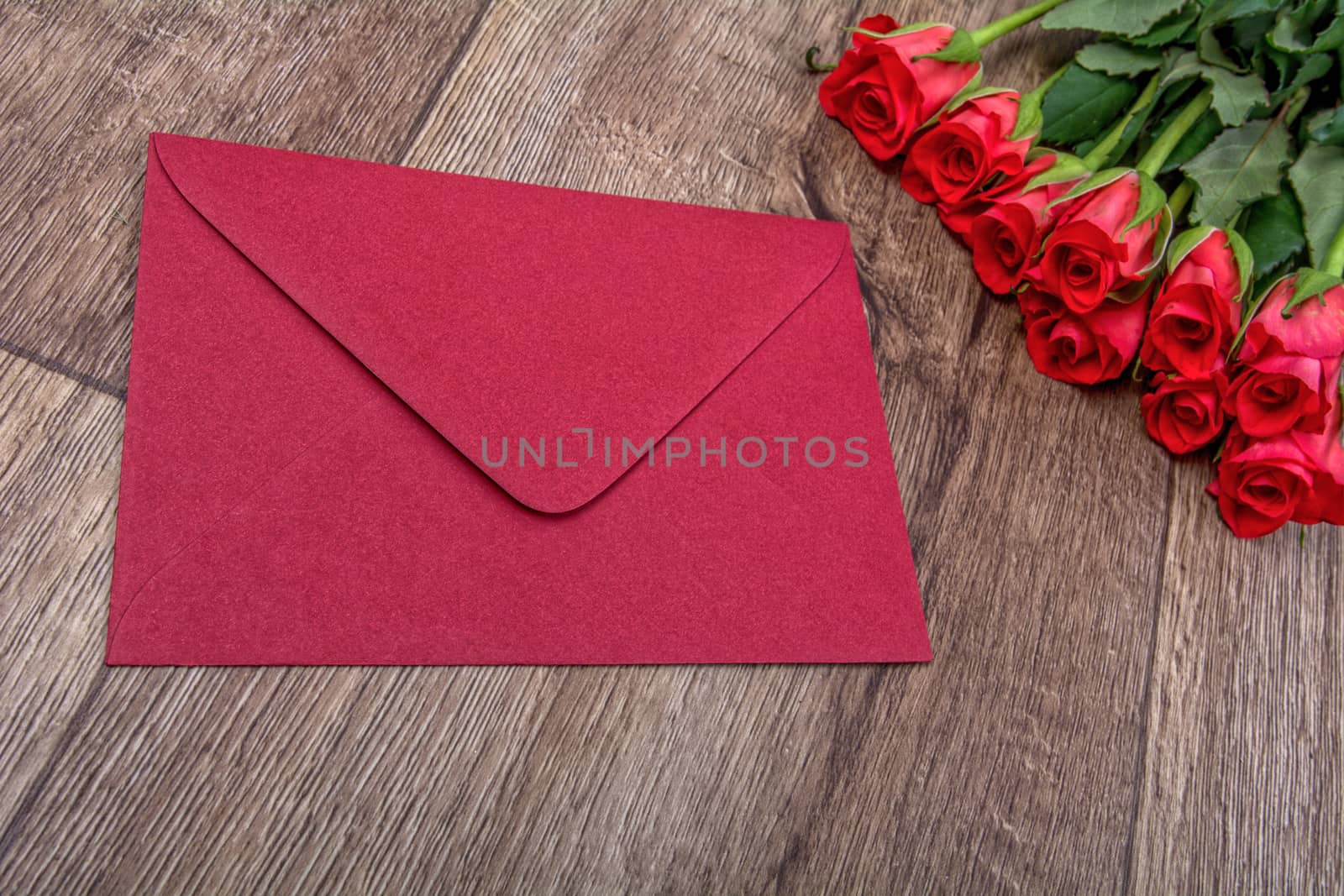 Red envelope and red roses on a wooden background