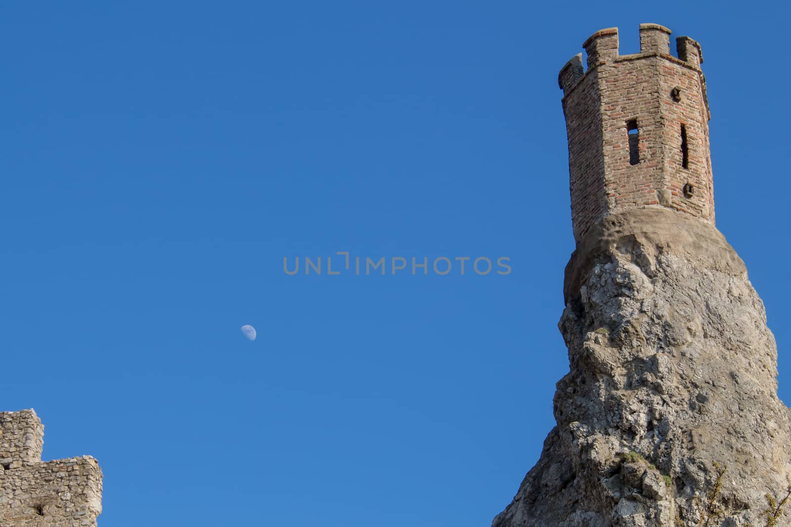 Part of ruins of castle Devin in Slovakia.  Maiden tower, built on the edge of a high rock. Bright blue sky with moon.