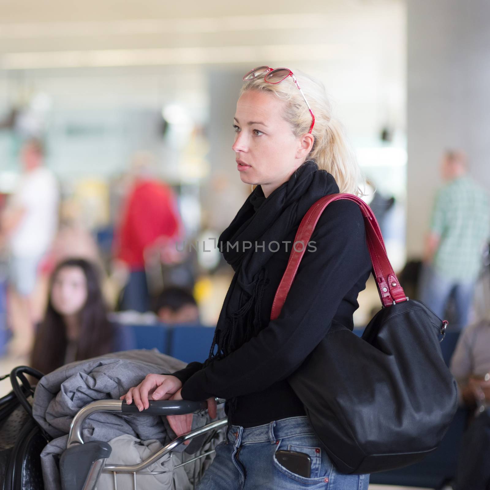 Female traveler using cell phone while waiting on airport. by kasto