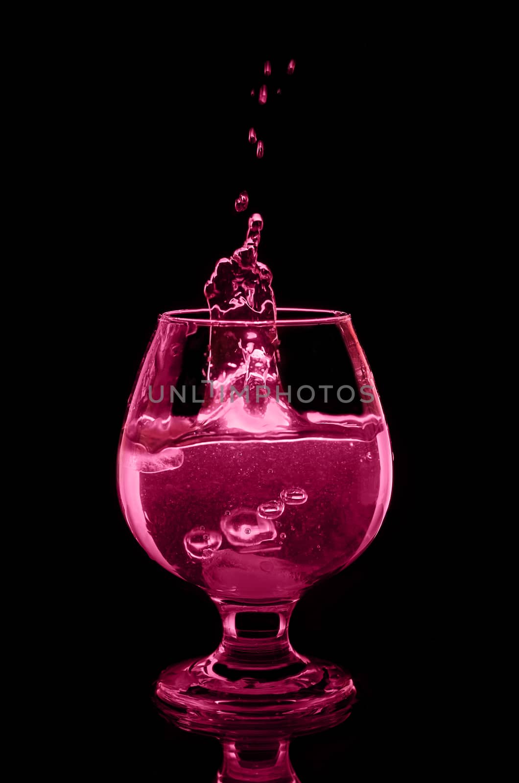 The cocktail in the glass and splashes on black background by Gaina