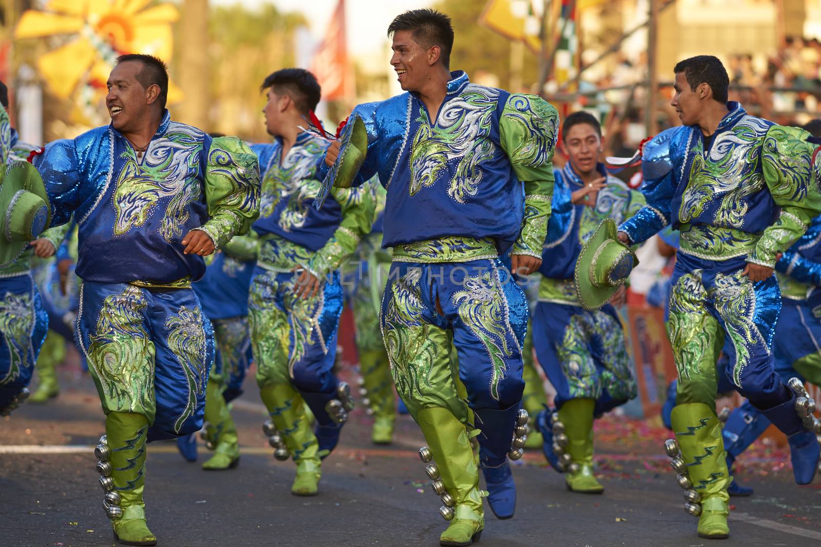 Male members of a Caporales dance group in ornate green and blue costumes performing at the annual Carnaval Andino con la Fuerza del Sol in Arica, Chile.