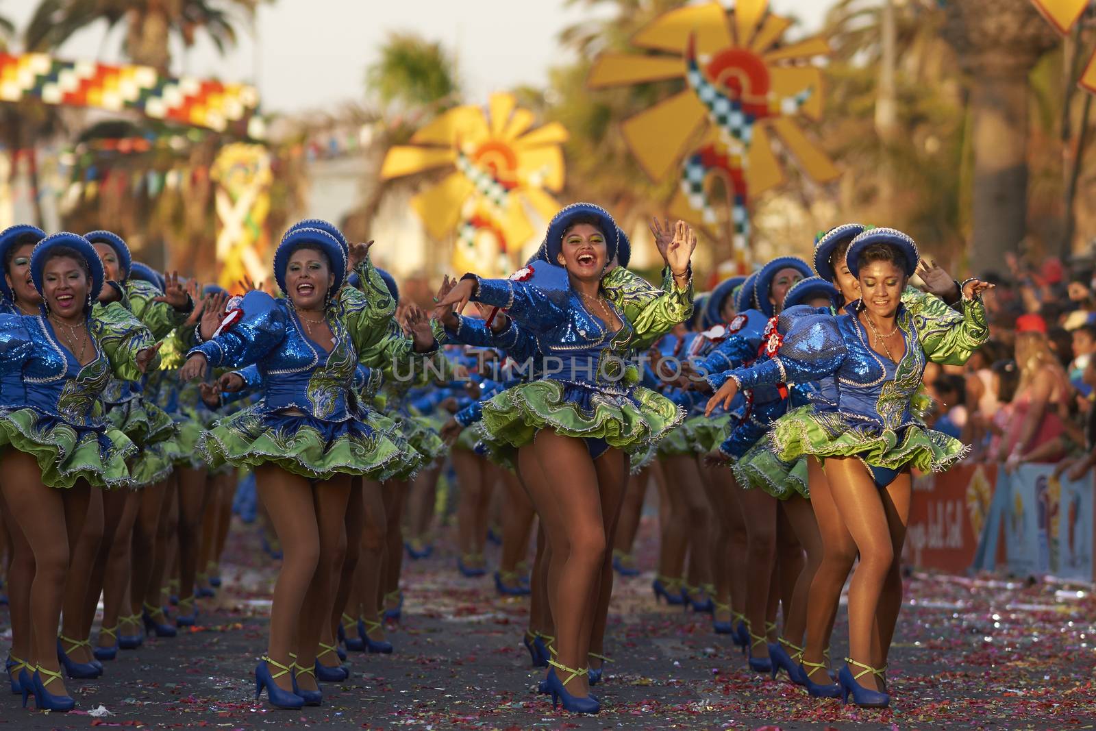 Female members of a Caporales dance group in ornate green and blue costumes performing at the annual Carnaval Andino con la Fuerza del Sol in Arica, Chile.