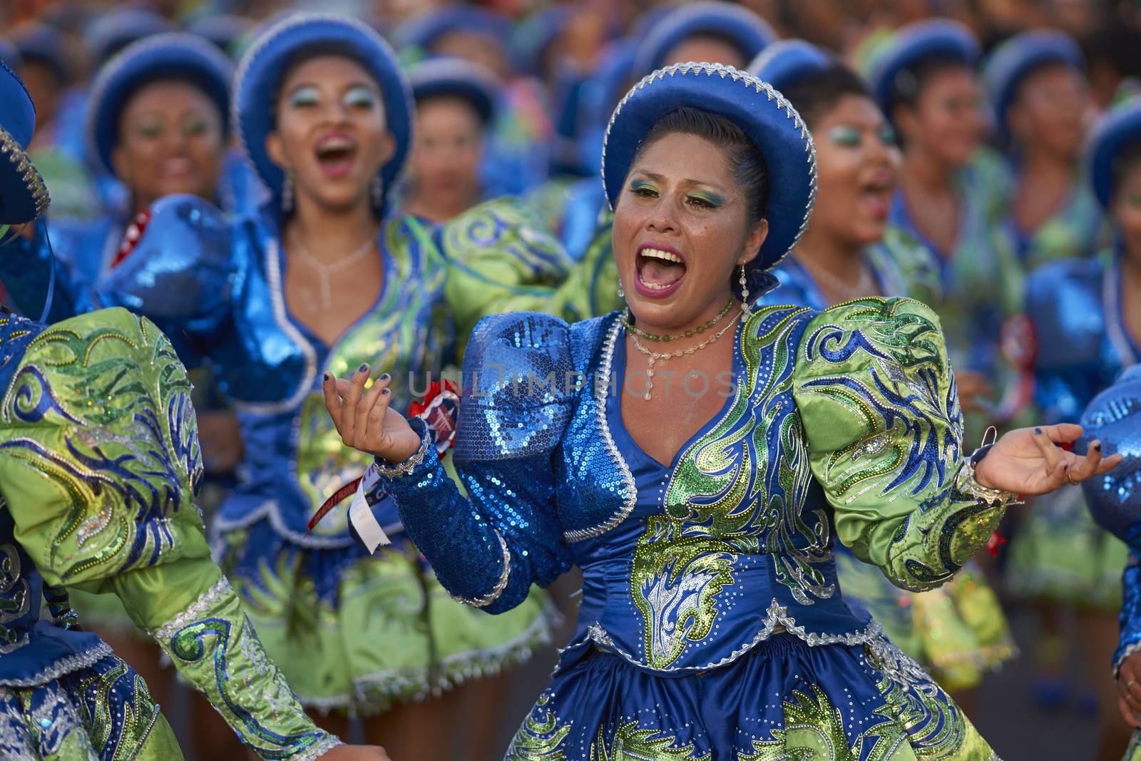 Female members of a Caporales dance group in ornate green and blue costumes performing at the annual Carnaval Andino con la Fuerza del Sol in Arica, Chile.