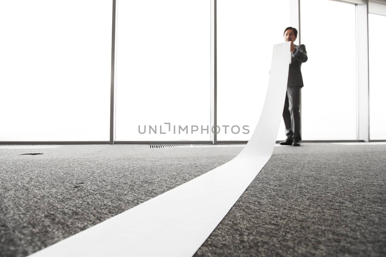 Office worker unrolling long sheet of paper