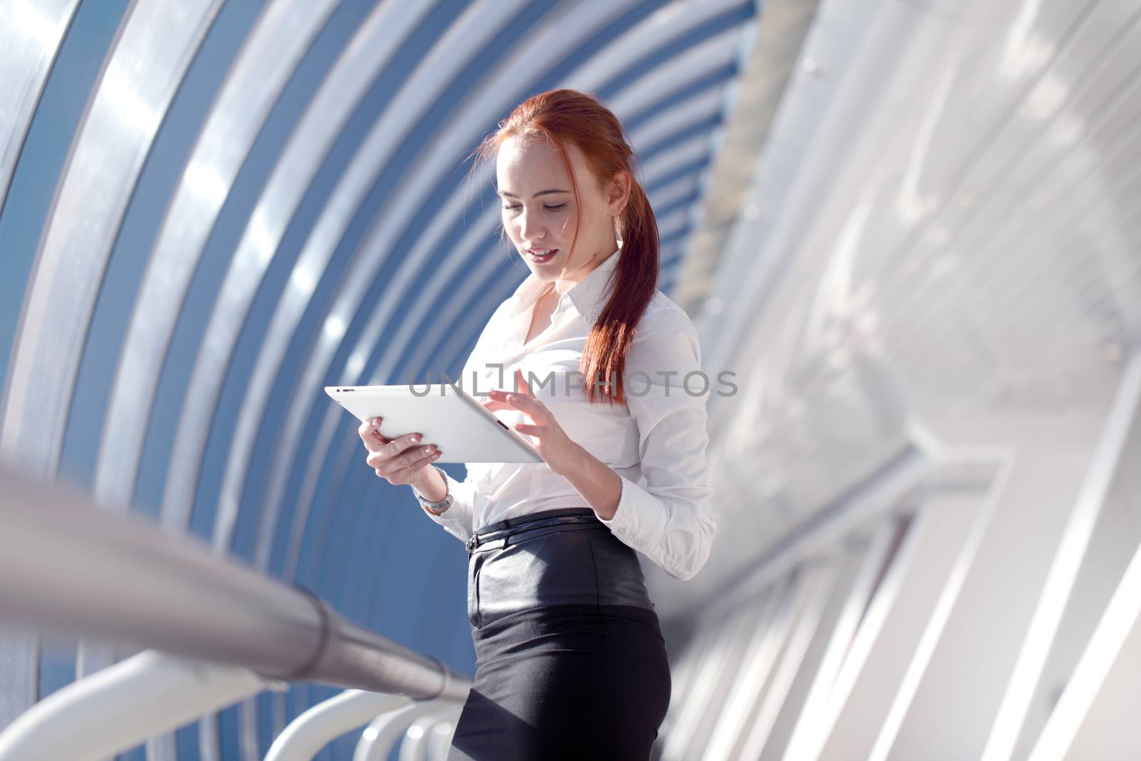 Beautiful modern businesswoman using tablet computer inside modern building