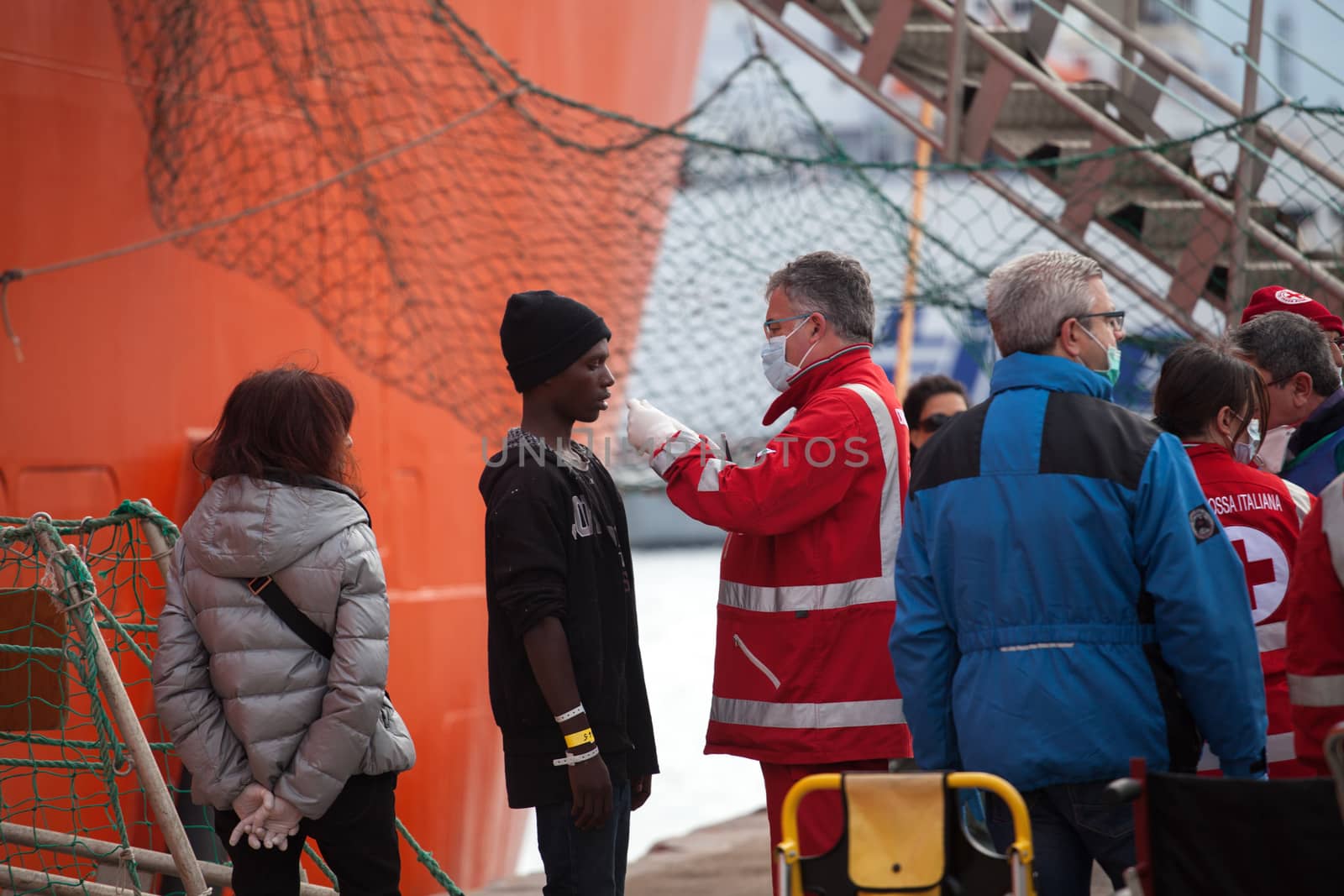 ITALY, Palermo: A medical workers assists a migrant as he gets off a ship in Palermo, Italy on March 19, 2016.712 migrants have arrived at the port of Palermo, on the military Norwegian ship Siem Pilot on March 19, 2016. Among them 598 men, 51 women, and 63 children came from 30 different nationalities including Nigeria, Senegal, Guinea, Sierra Leone and other Sub-saharan countries.