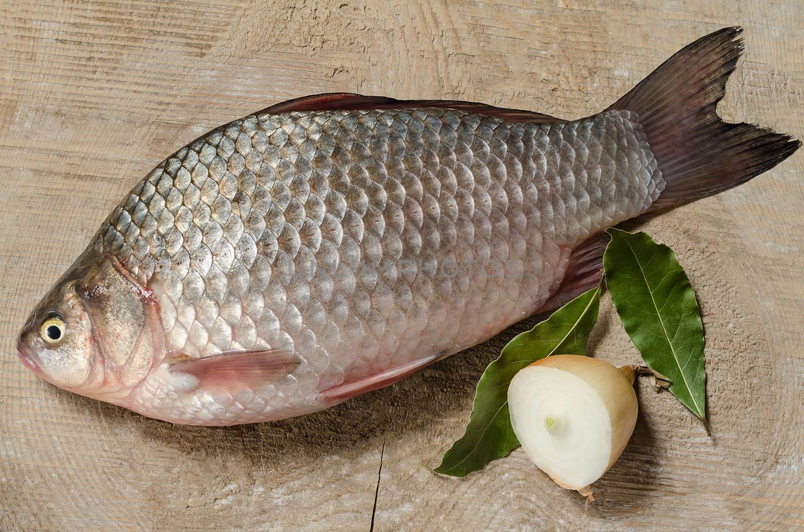 Raw fish on a natural textures wooden background, onion and spices.