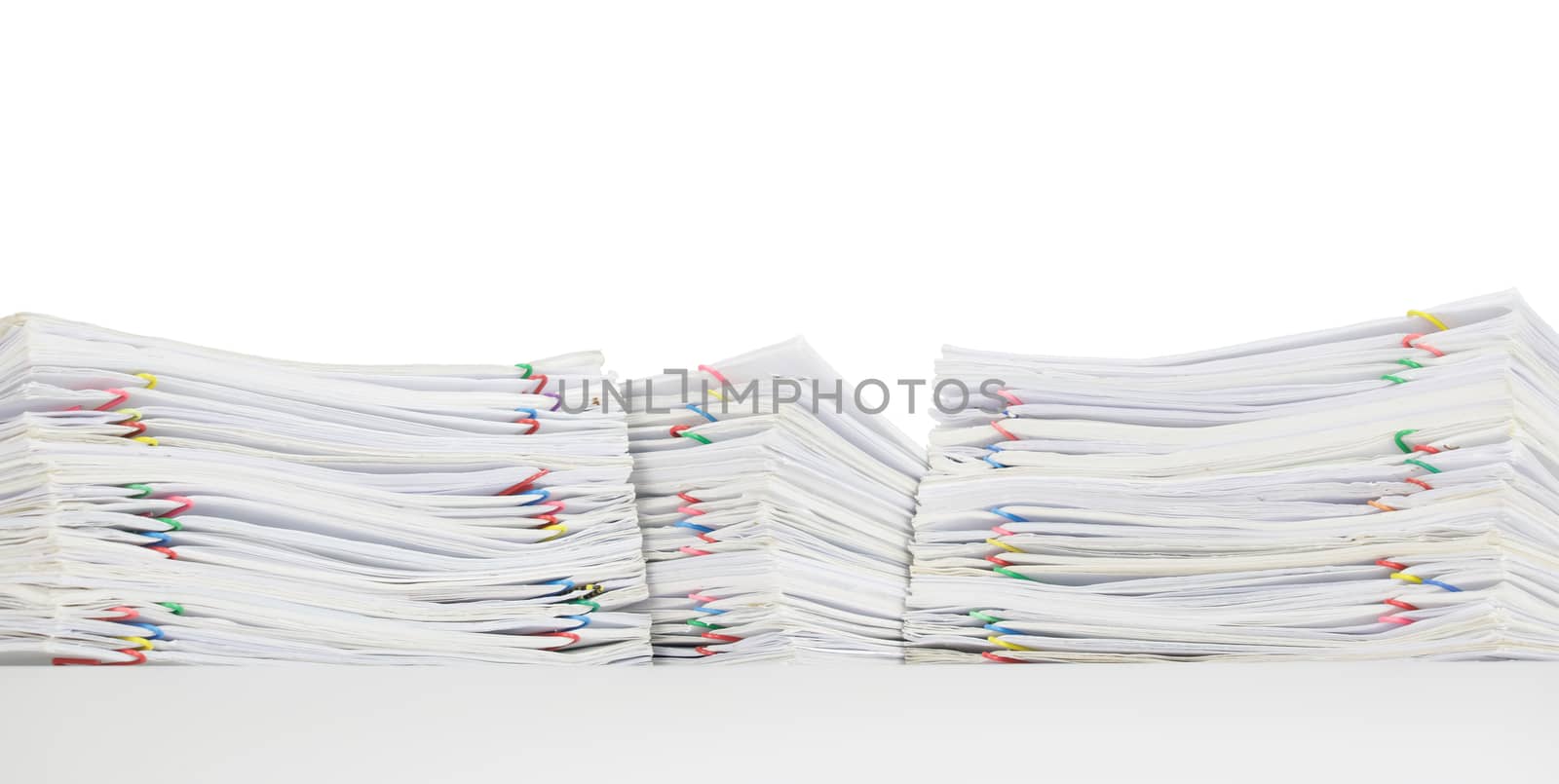 Overload of paperwork with colorful paperclip on white table and isolated on white background.