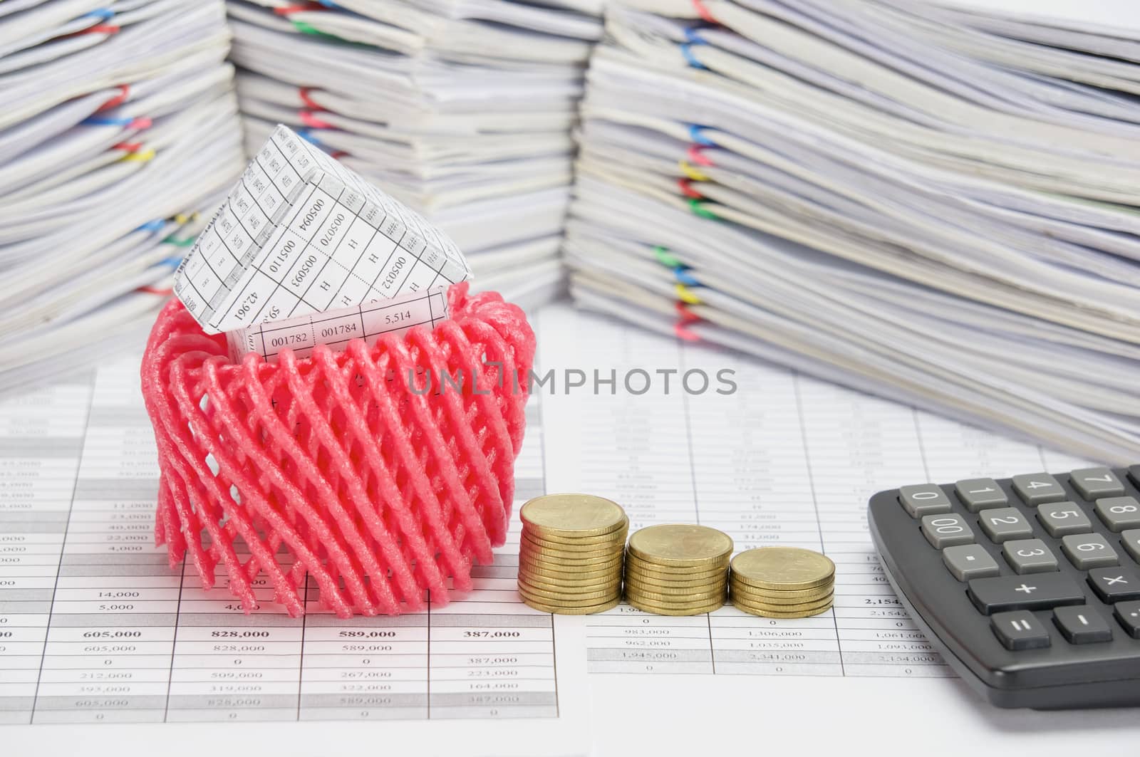 House with pink foam protection and step pile of gold coins on finance account have calculator and overload of paperwork with colorful paperclip as background.