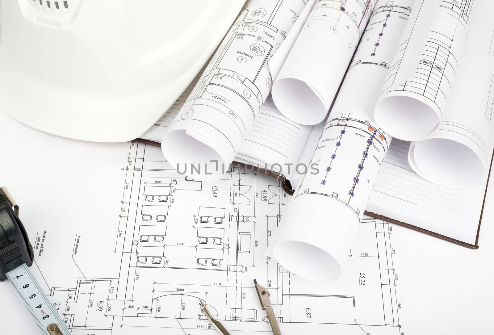 Architecture plan and rolls of blueprints with hard hat and divider. Building concept