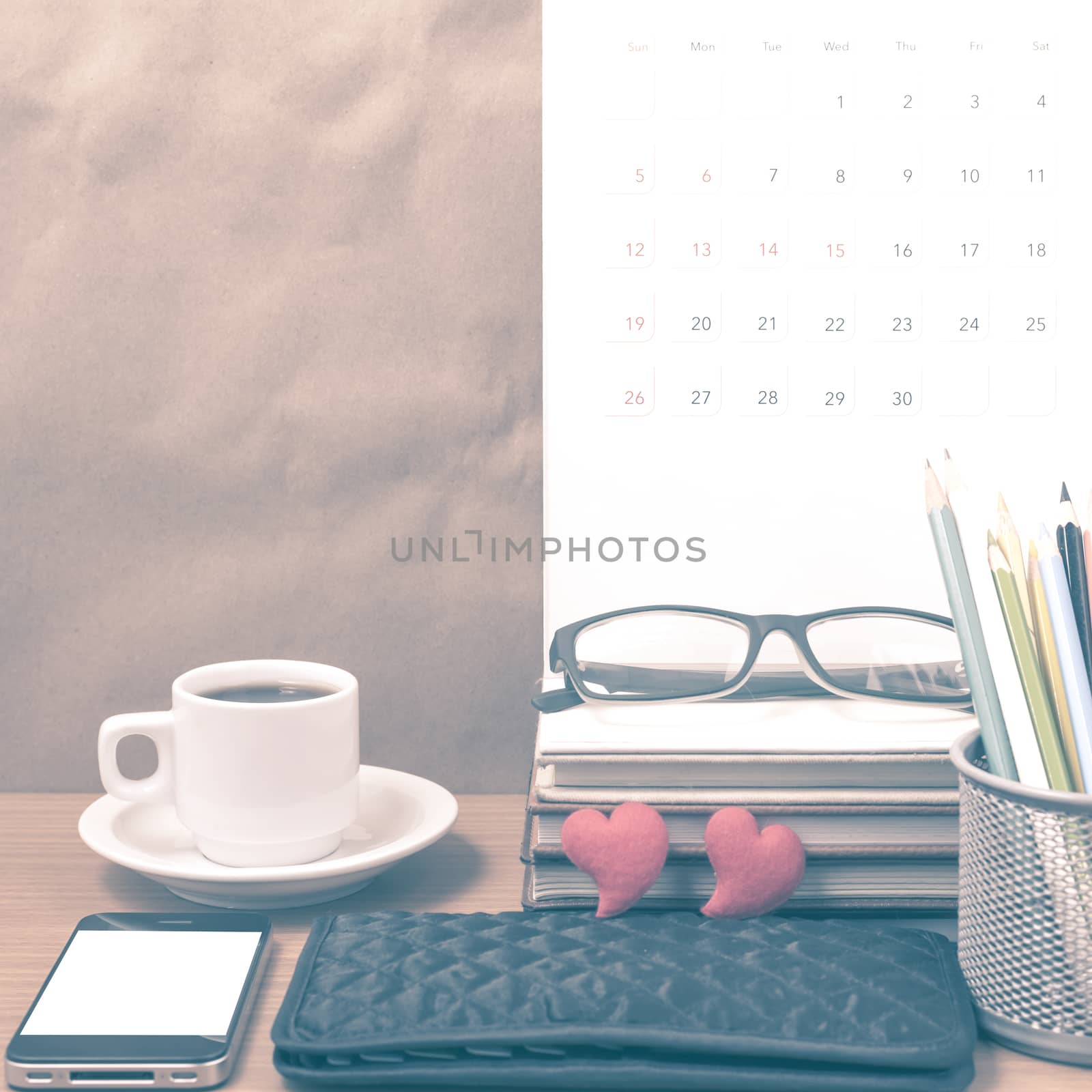 office desk : coffee with phone,wallet,calendar,color pencil box,stack of book,heart,eyeglasses on wood background vintage style