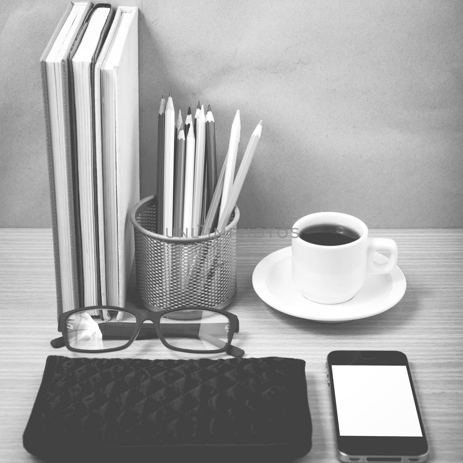 office desk : coffee with phone,stack of book,eyeglasses,wallet,color pencil box on wood background black and white color