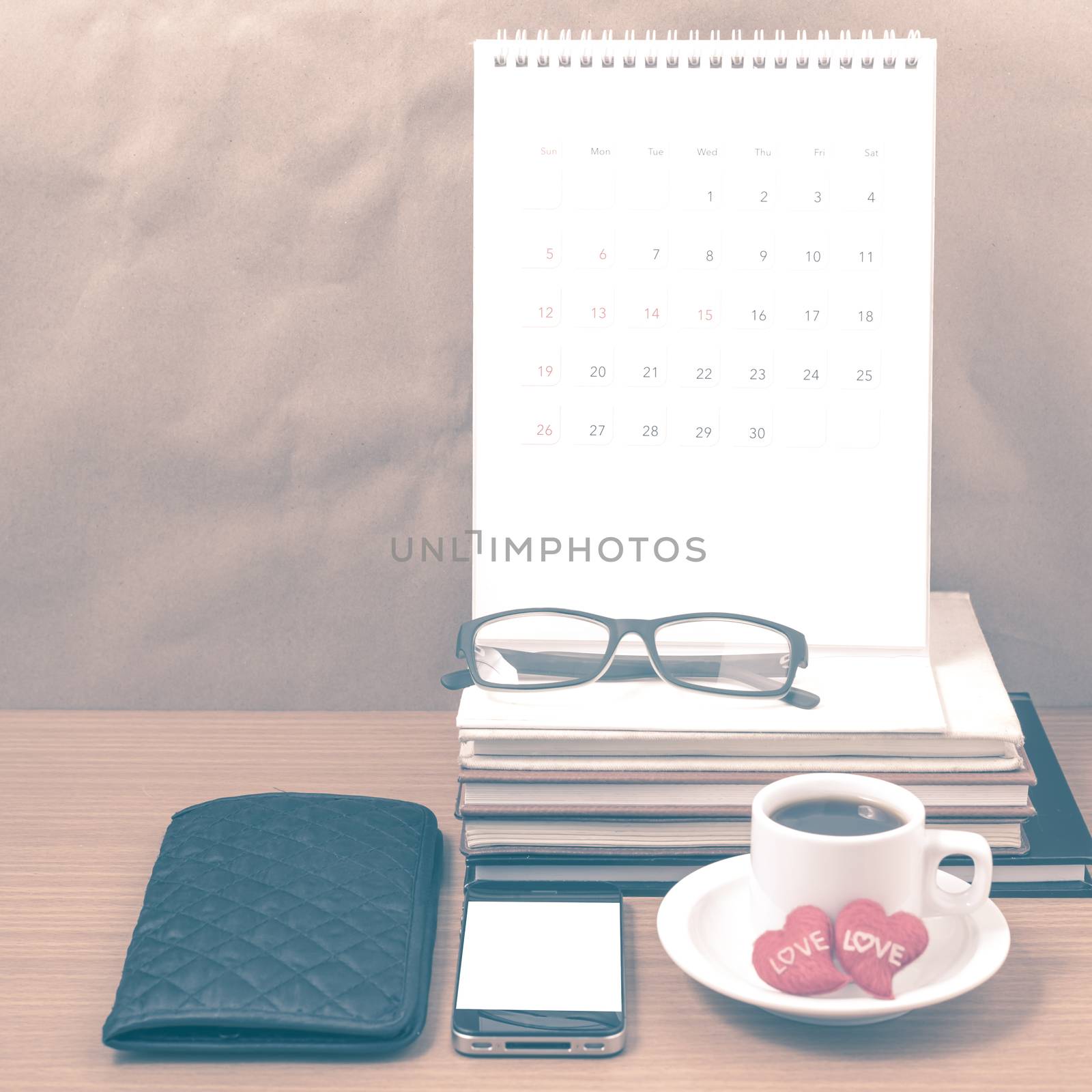 office desk : coffee with phone,wallet,calendar,heart,stack of book,eyeglasses on wood background vintage style