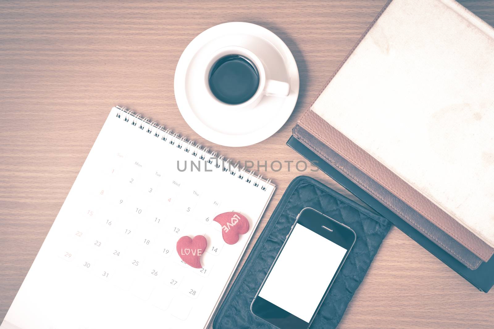 office desk : coffee with phone,wallet,calendar,heart,stack of book on wood background vintage style