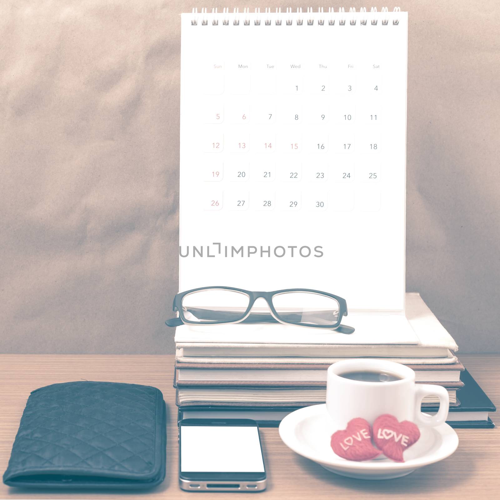 office desk : coffee with phone,wallet,calendar,heart,stack of book,eyeglasses on wood background vintage style