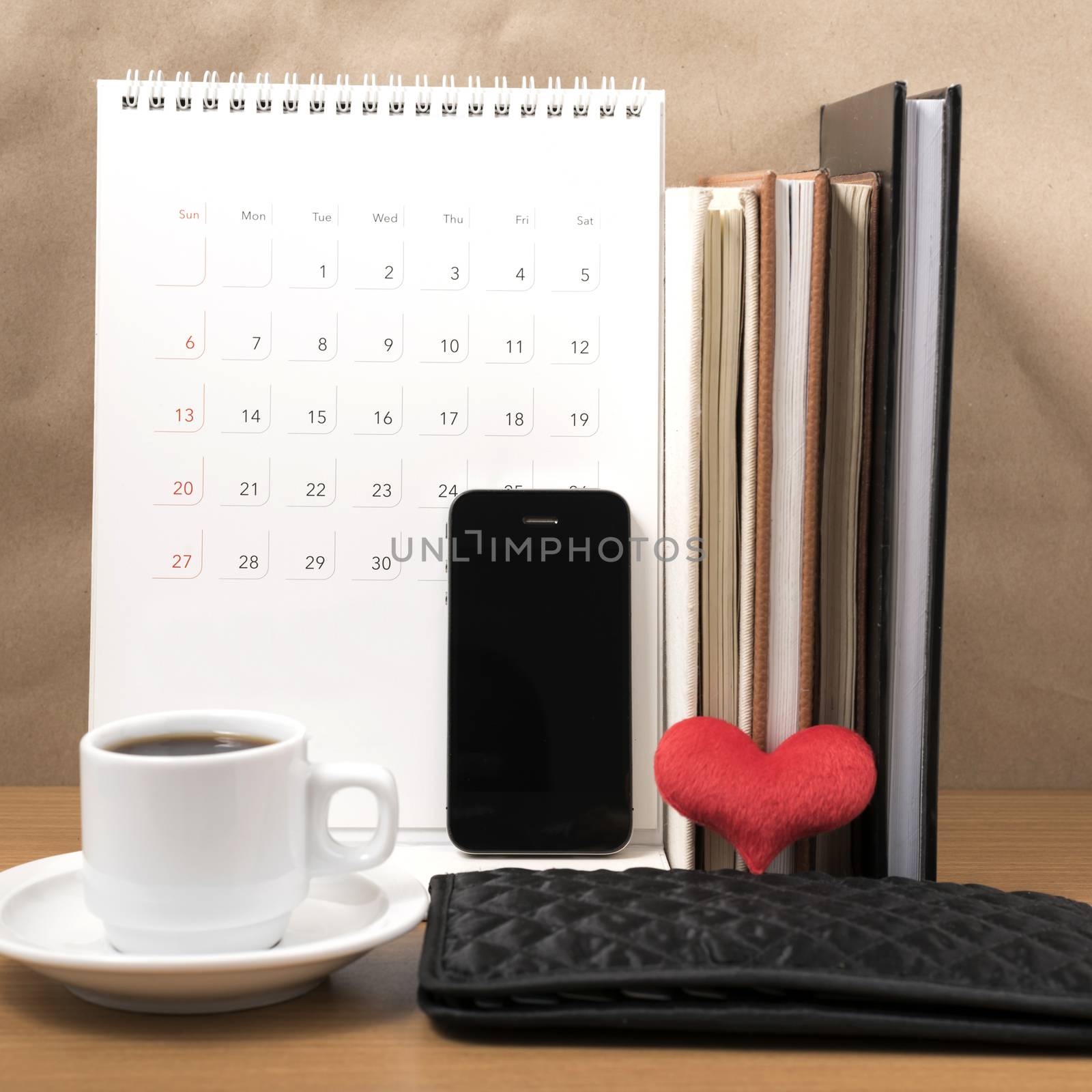 office desk : coffee with phone,wallet,calendar,heart,stack of book on wood background