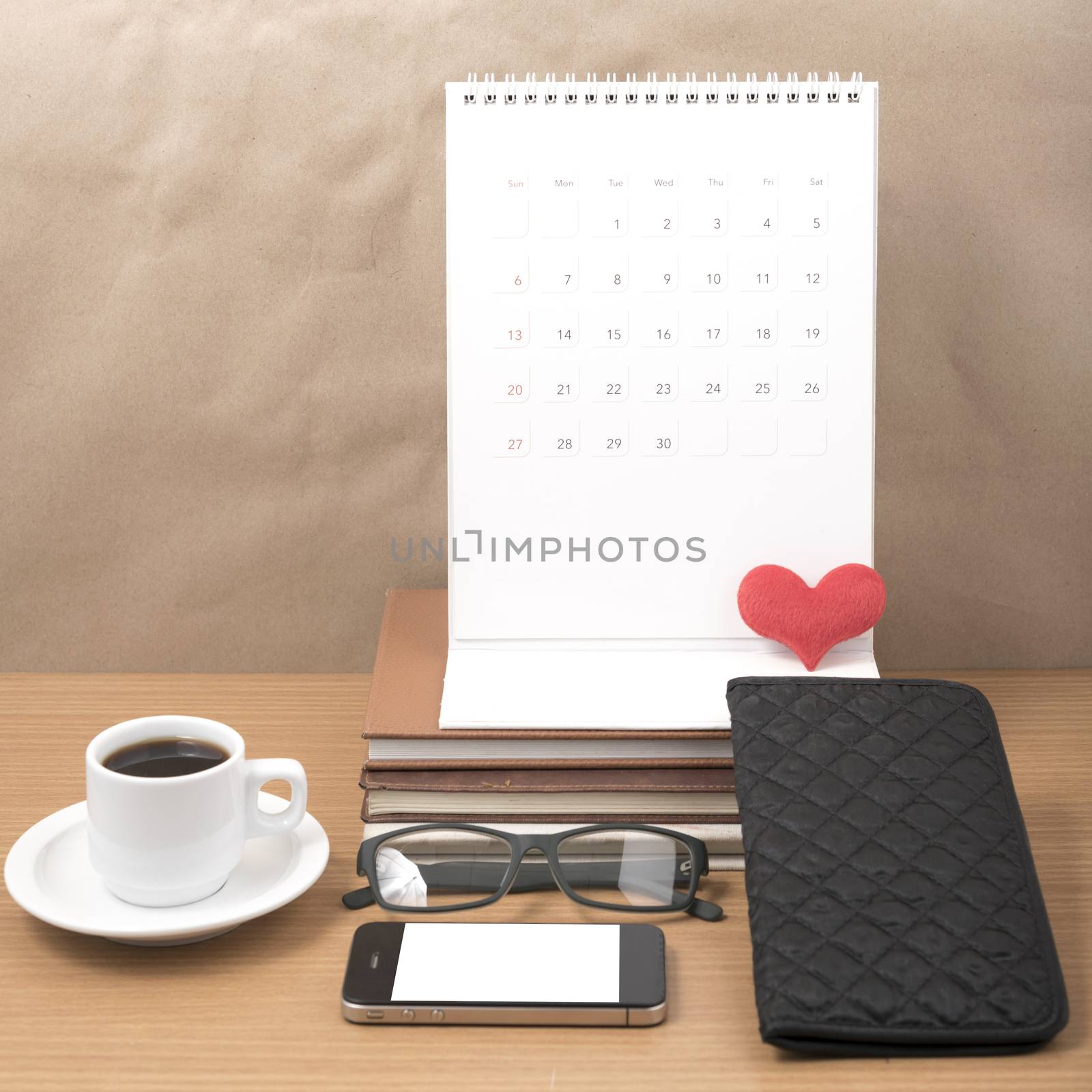 office desk : coffee with phone,stack of book,eyeglasses,wallet,calendar,heart on wood background