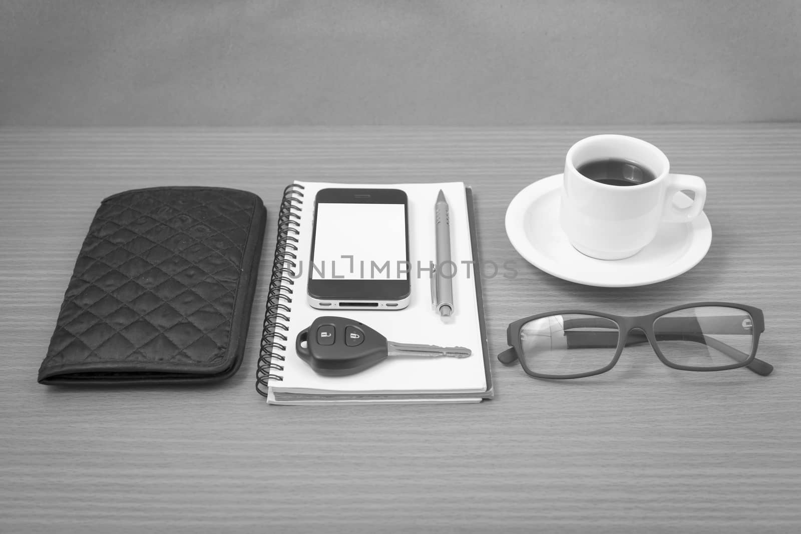 coffee and phone with notepad,car key,eyeglasses and wallet on wood table background black and white color