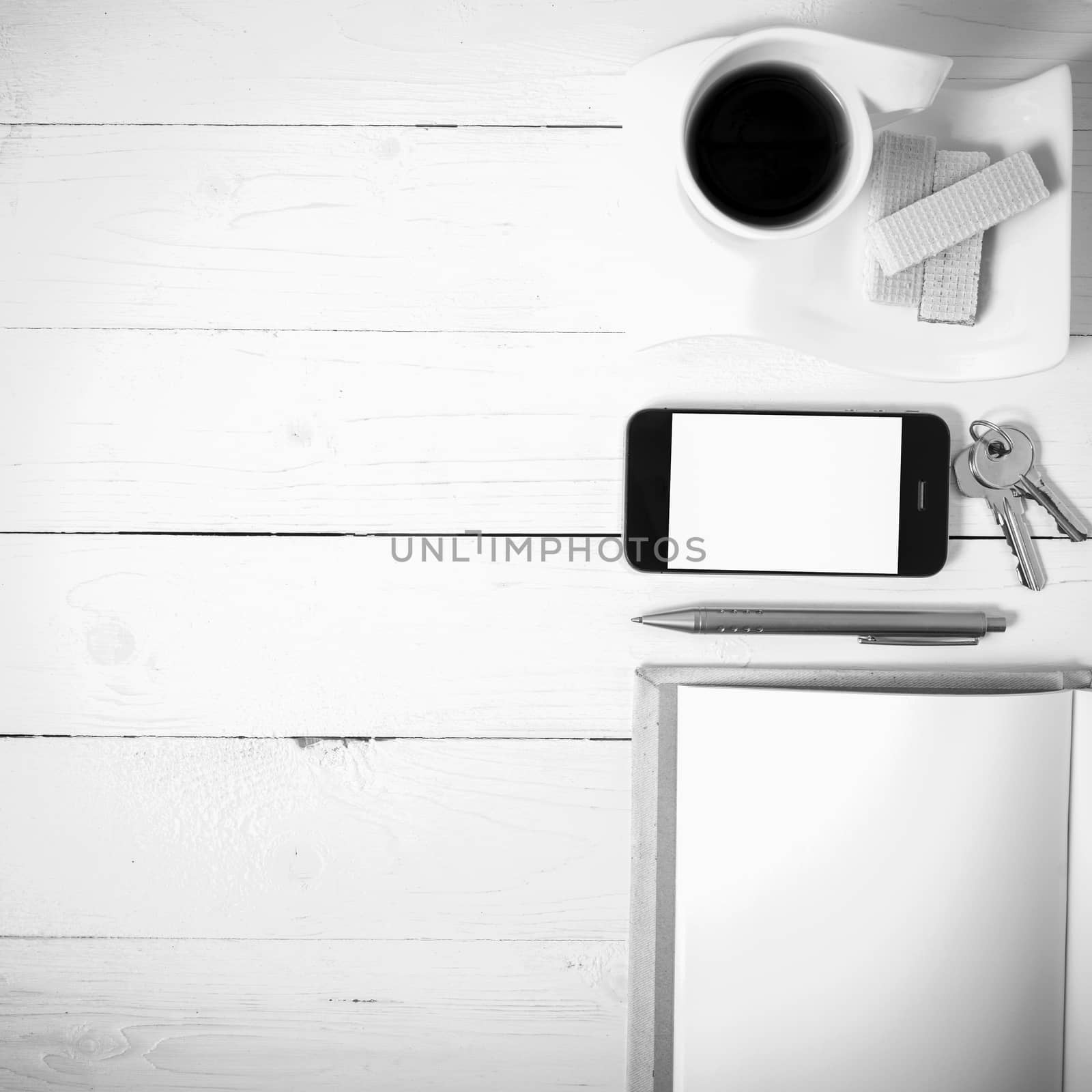 coffee cup with wafer,phone,key,notebook on white wood background black and white color