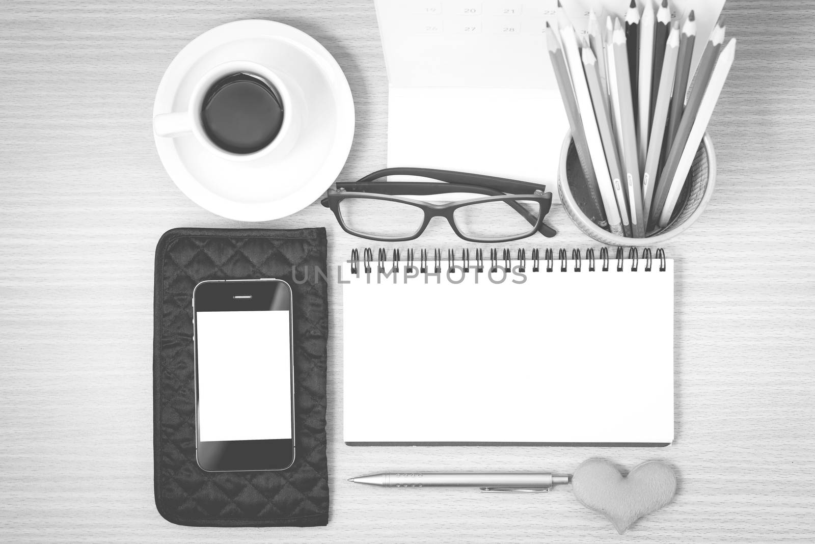 office desk : coffee with phone,wallet,calendar,color pencil box,notepad,heart on wood background black and white color