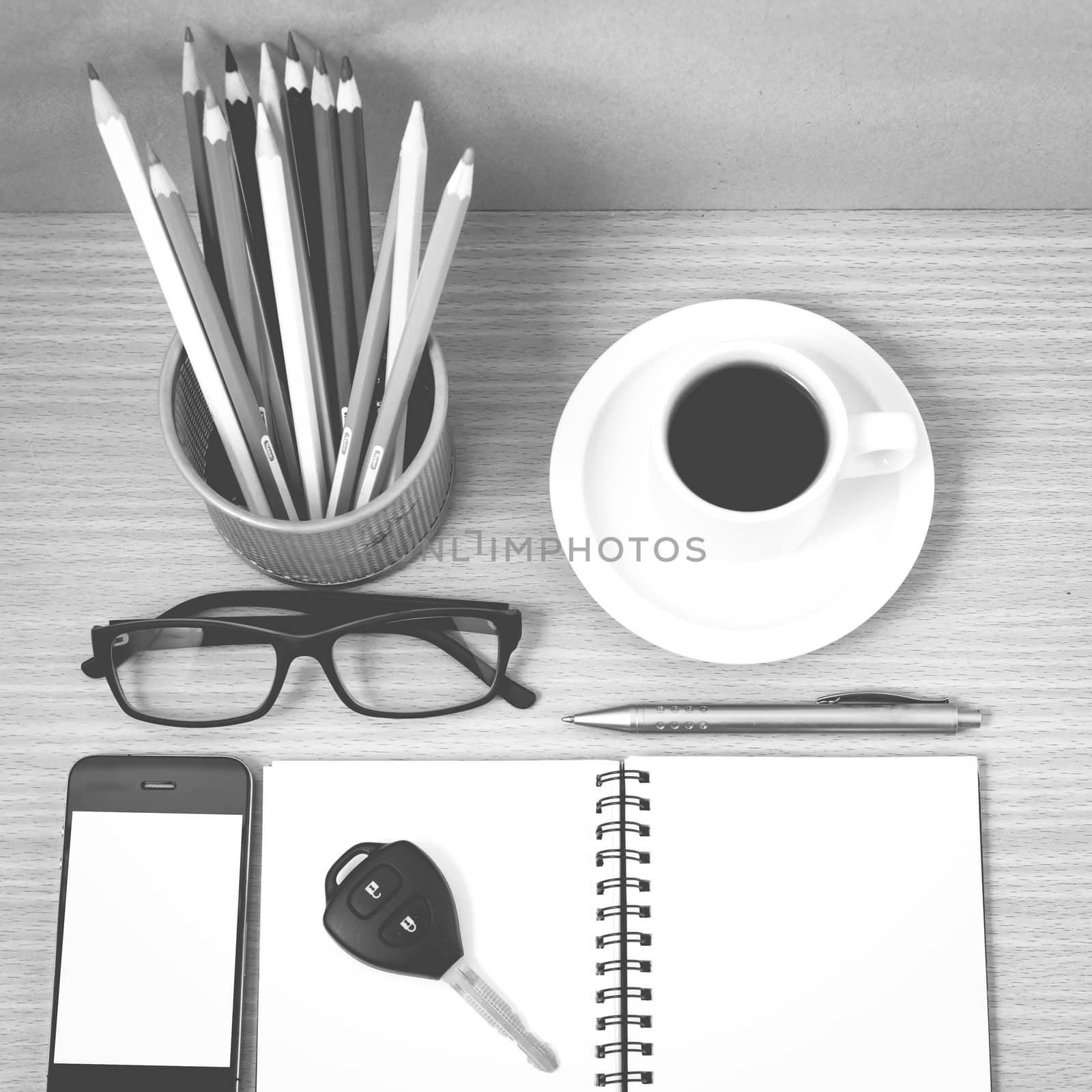 office desk : coffee and phone with key,eyeglasses,notepad,pencil box black and white color