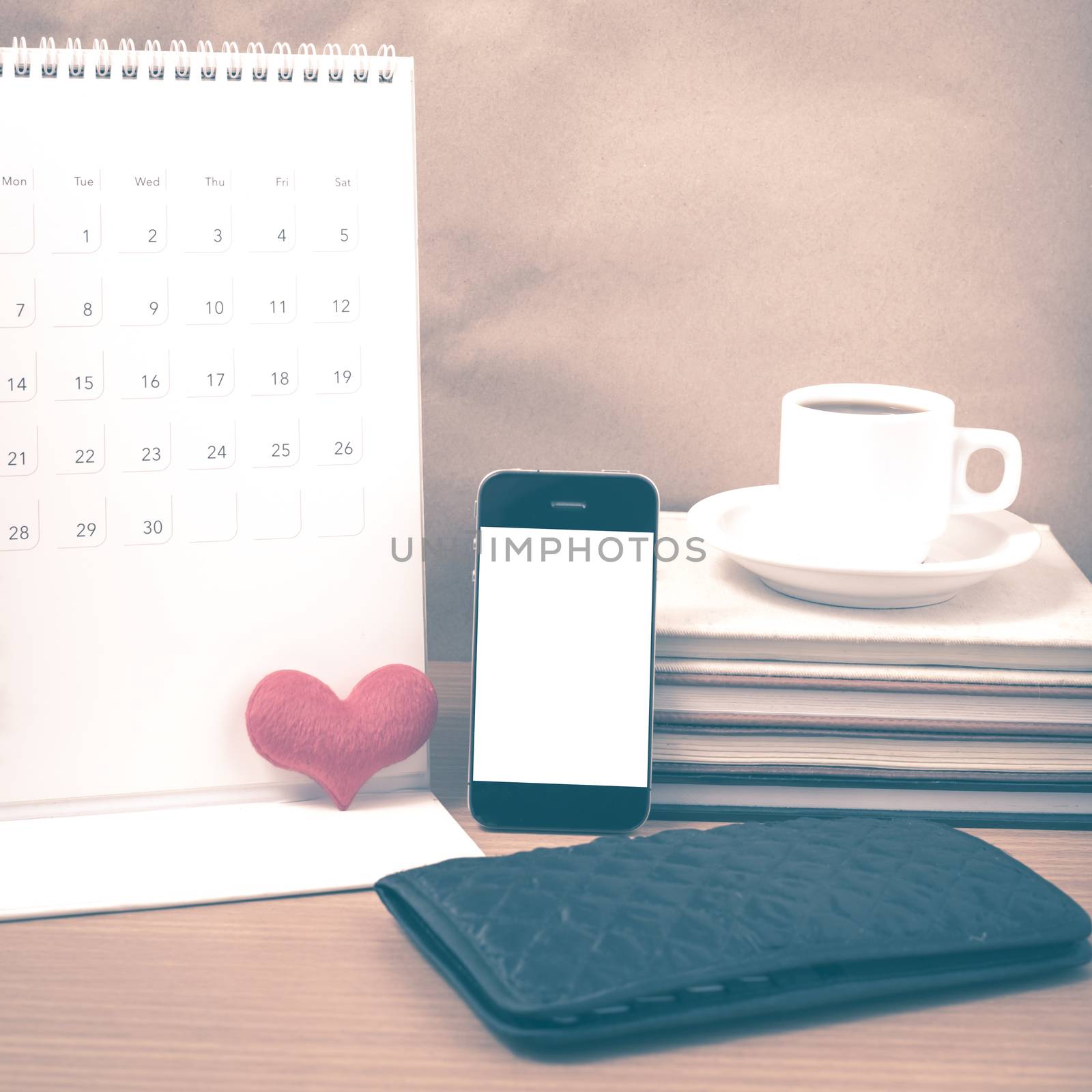 office desk : coffee with phone,wallet,calendar,heart,stack of book on wood background vintage style