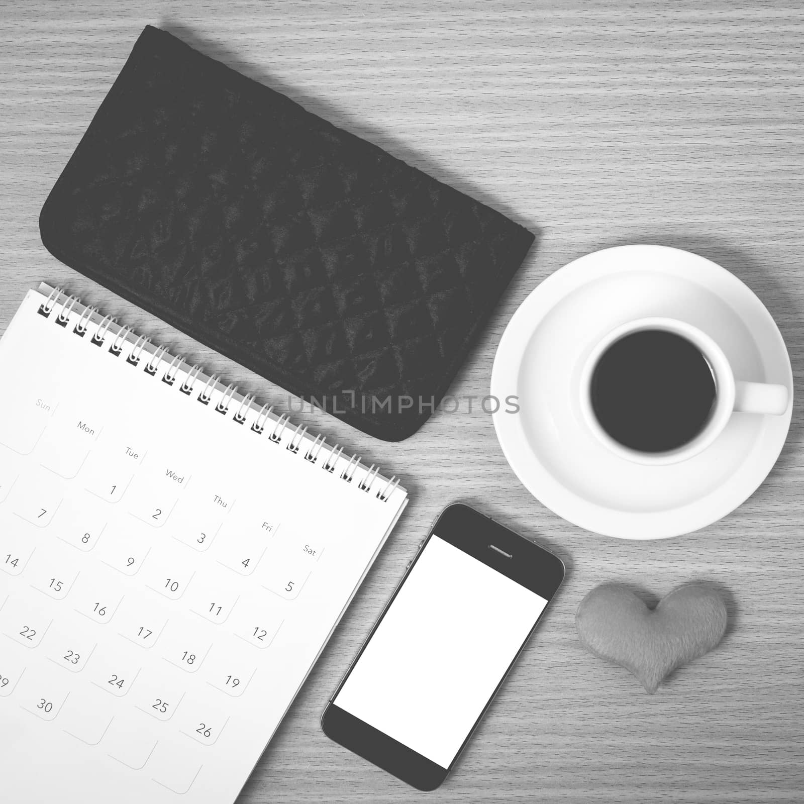 office desk : coffee with phone,wallet,calendar,heart on wood background black and white color