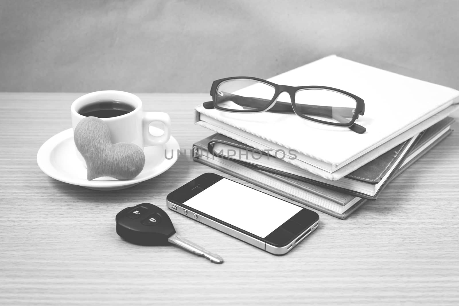 office desk : coffee and phone with car key,eyeglasses,stack of book,heart black and white color